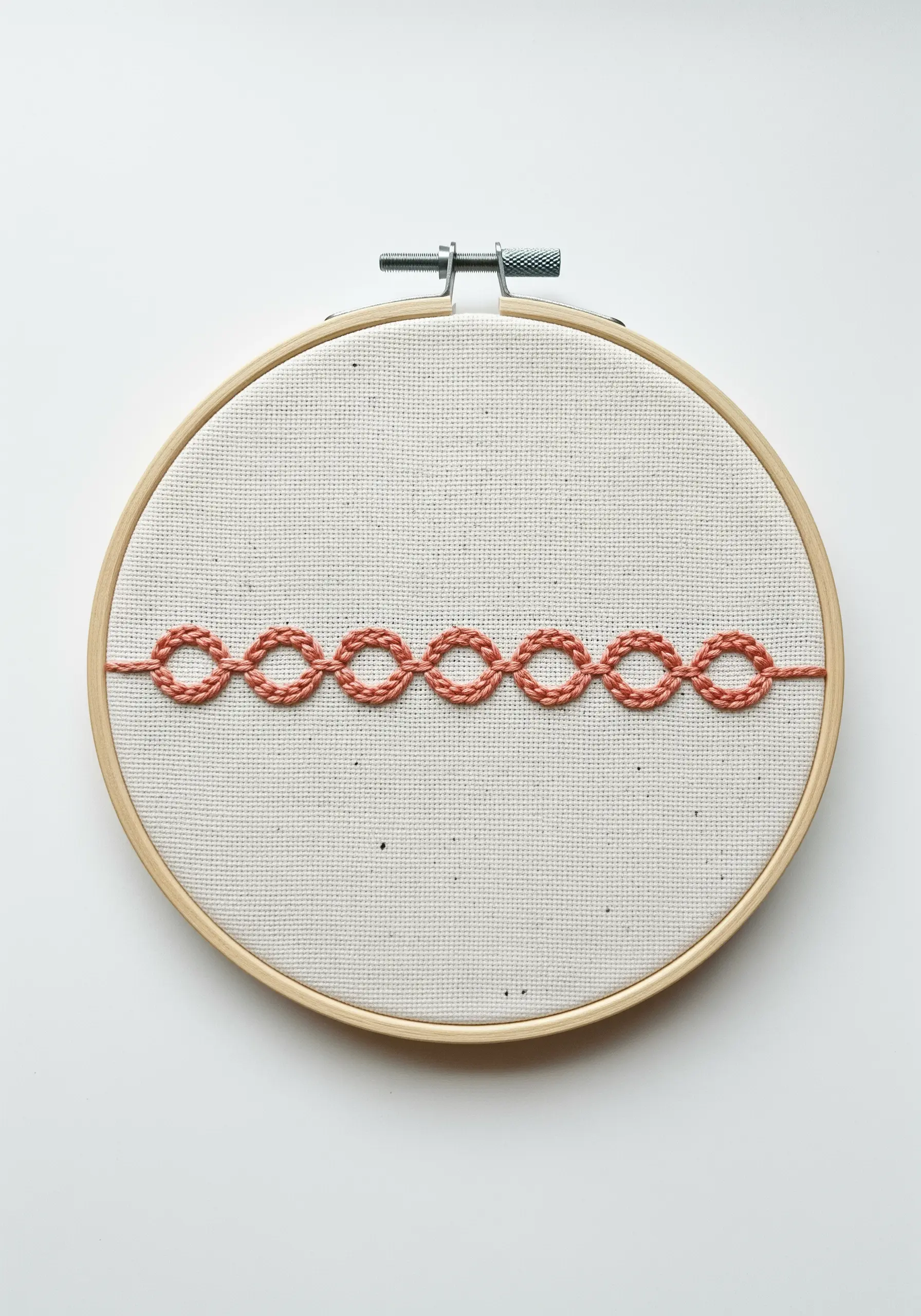 A clean, horizontal border created with the open chain stitch in a coral color.