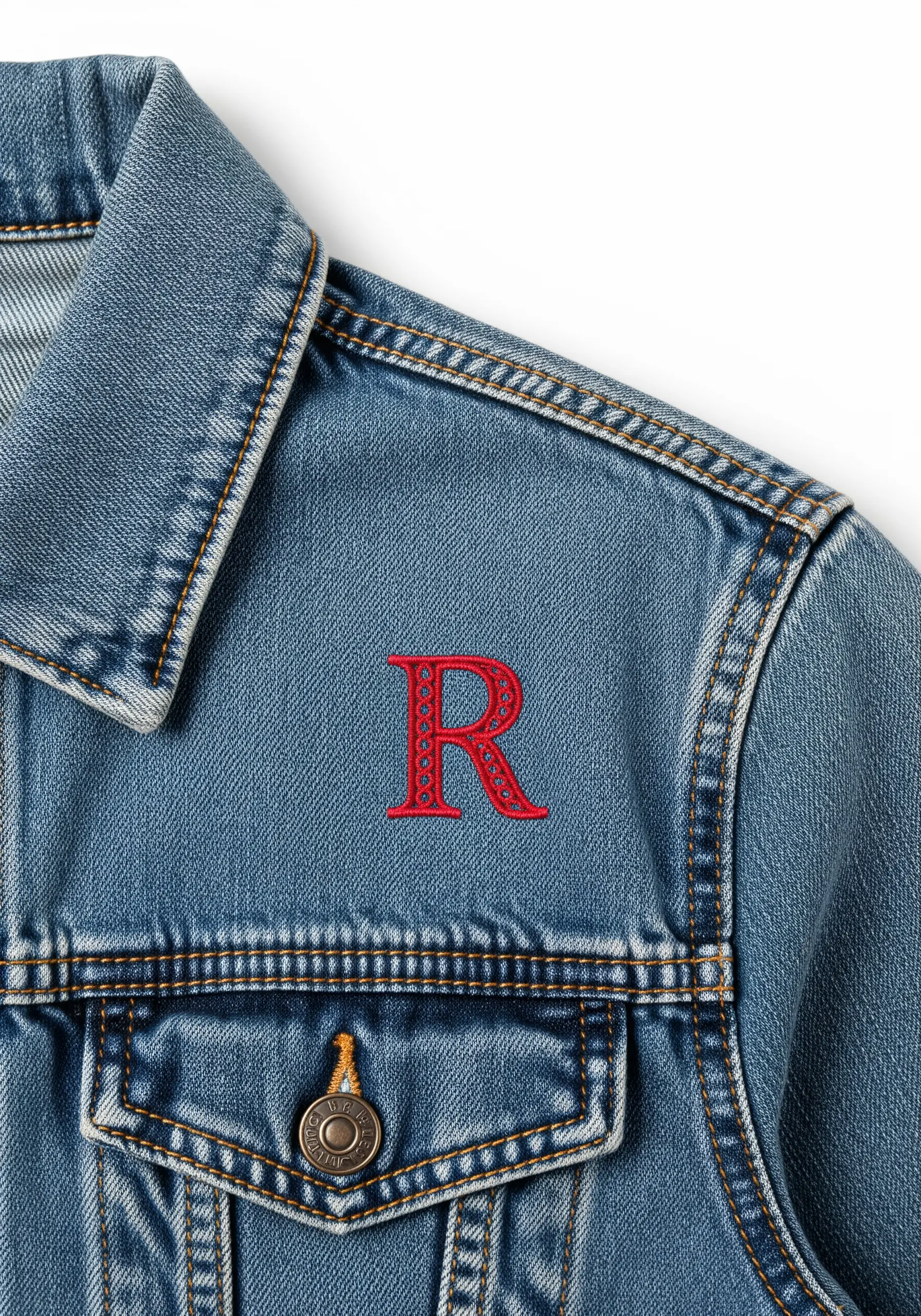 A red embroidered letter 'R' with an intricate pattern on the front of a denim jacket