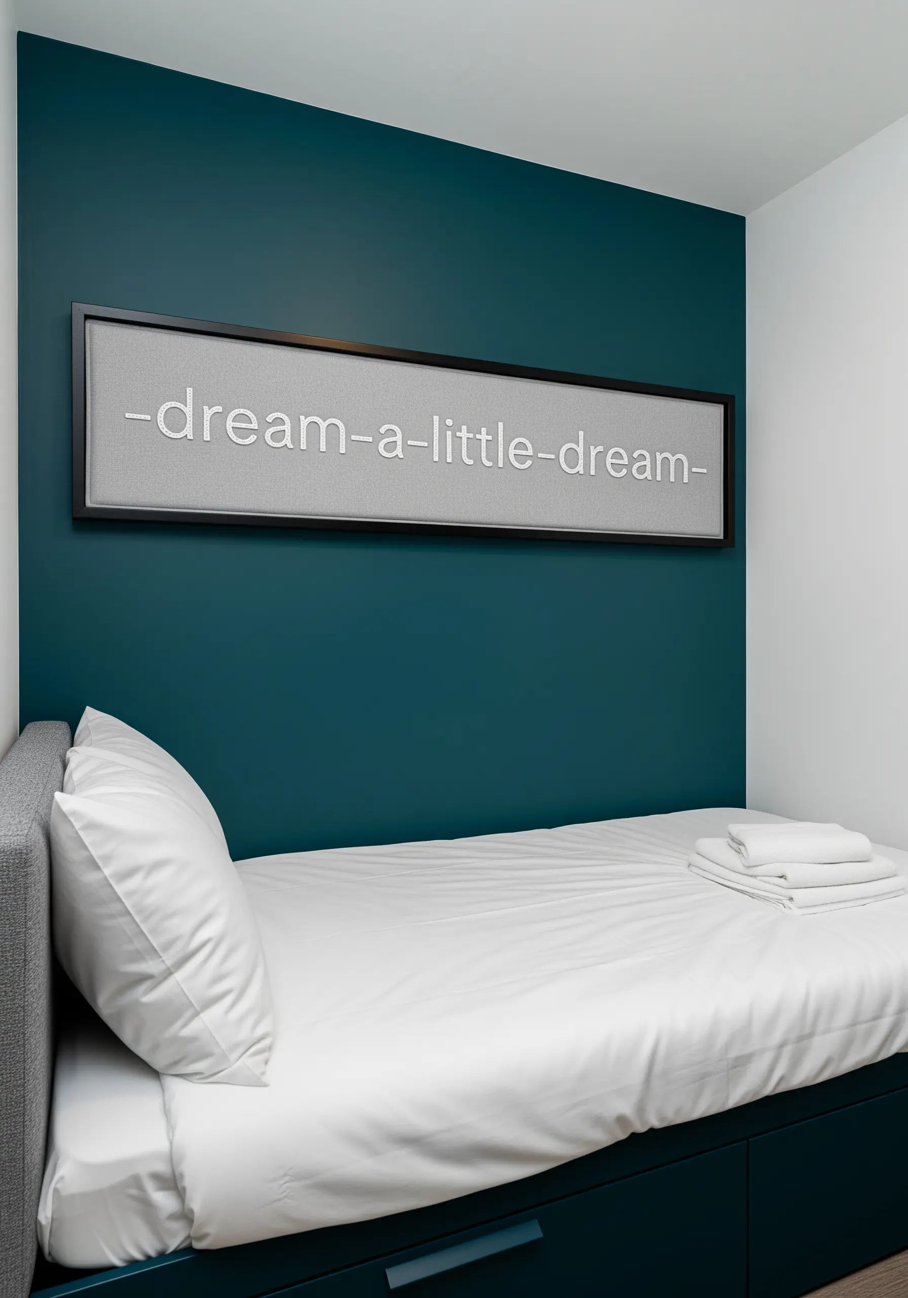 A long rectangular frame with the embroidered phrase '-dream-a-little-dream-' on gray fabric.