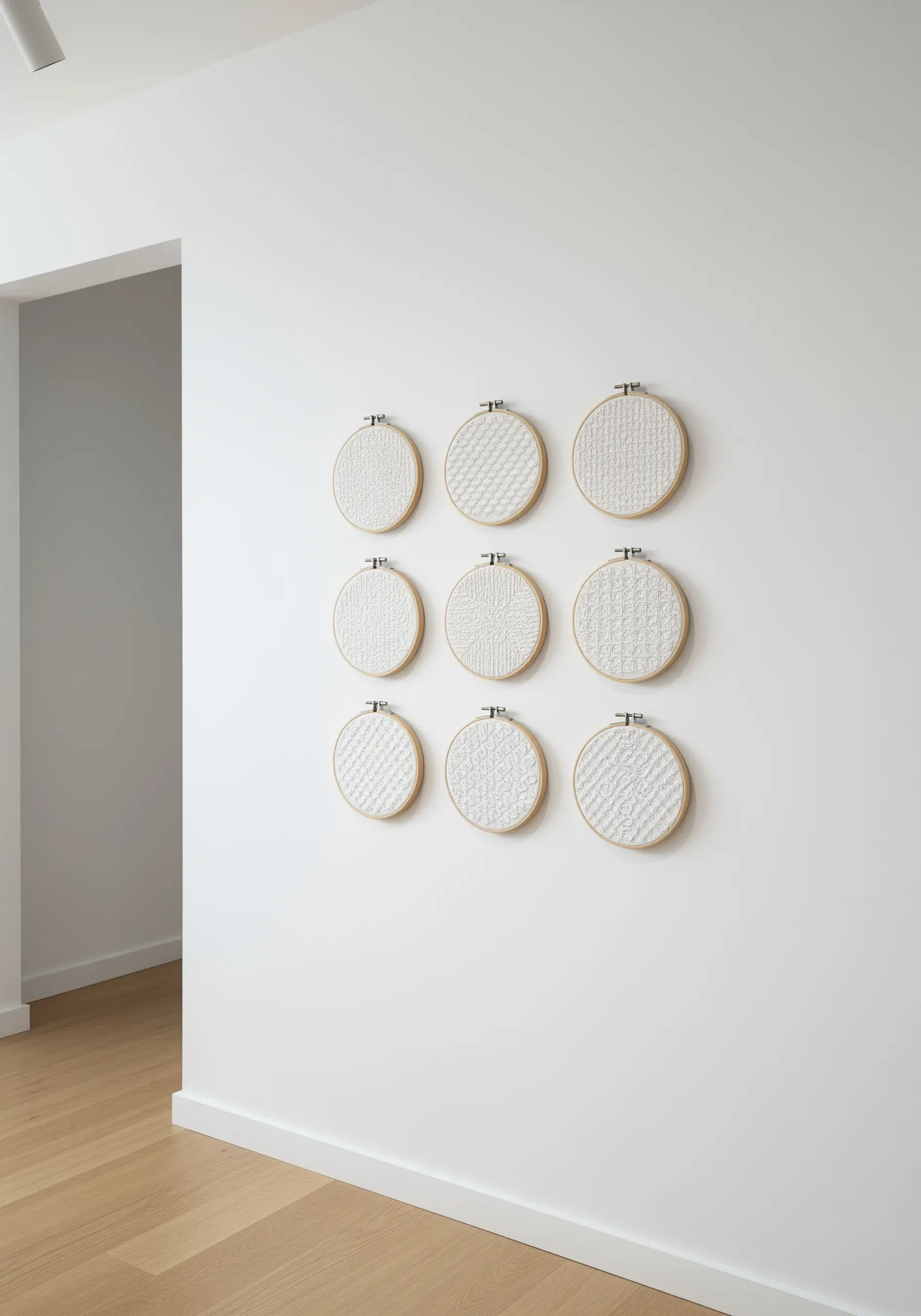 A 3x3 grid of embroidery hoops with white-on-white textural stitch patterns.