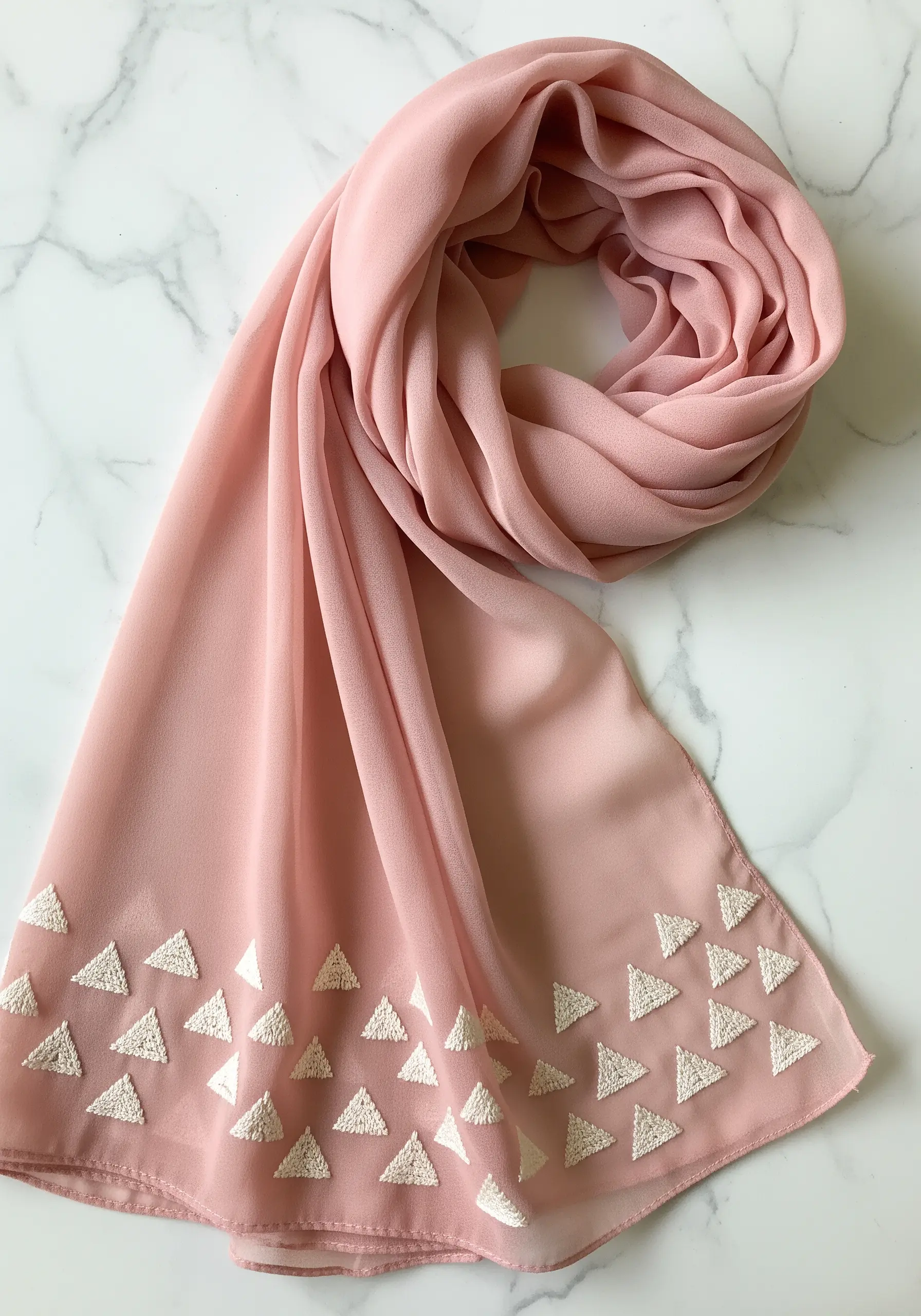 Scattered white satin-stitched triangles on a pink chiffon scarf.