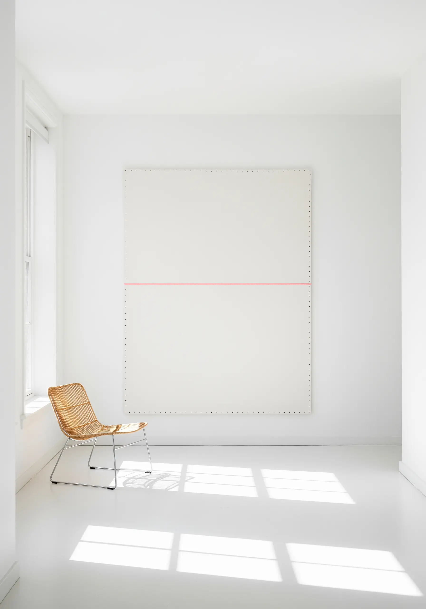 A large white canvas divided by a single, perfectly straight red embroidered line.