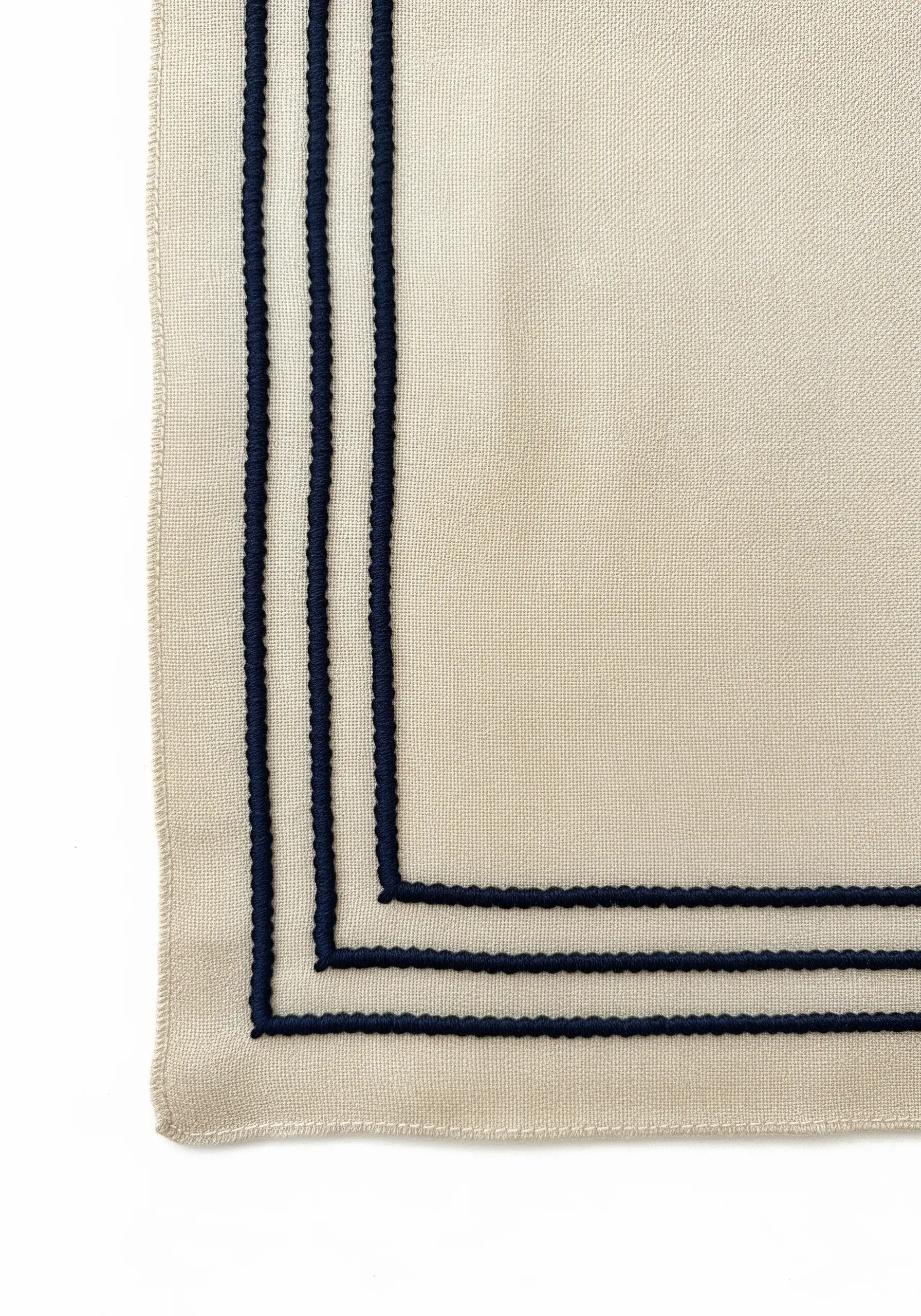 Three parallel navy blue corded stitch lines on a cream fabric corner.