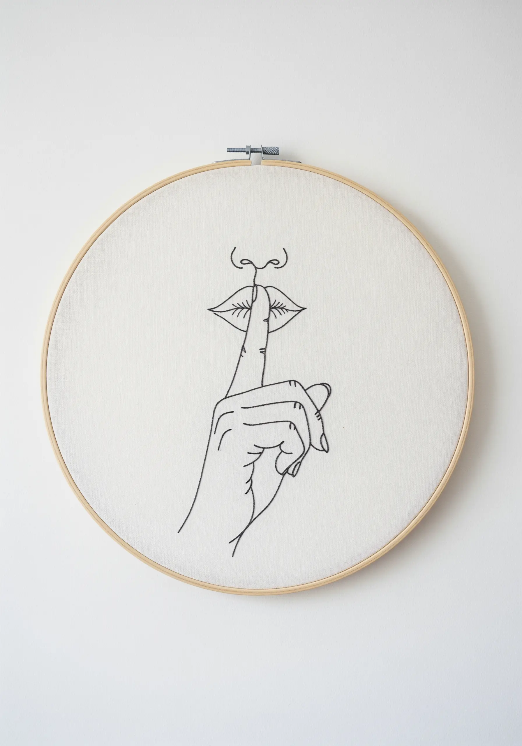 A minimalist black line art embroidery of a finger held to lips on white fabric.