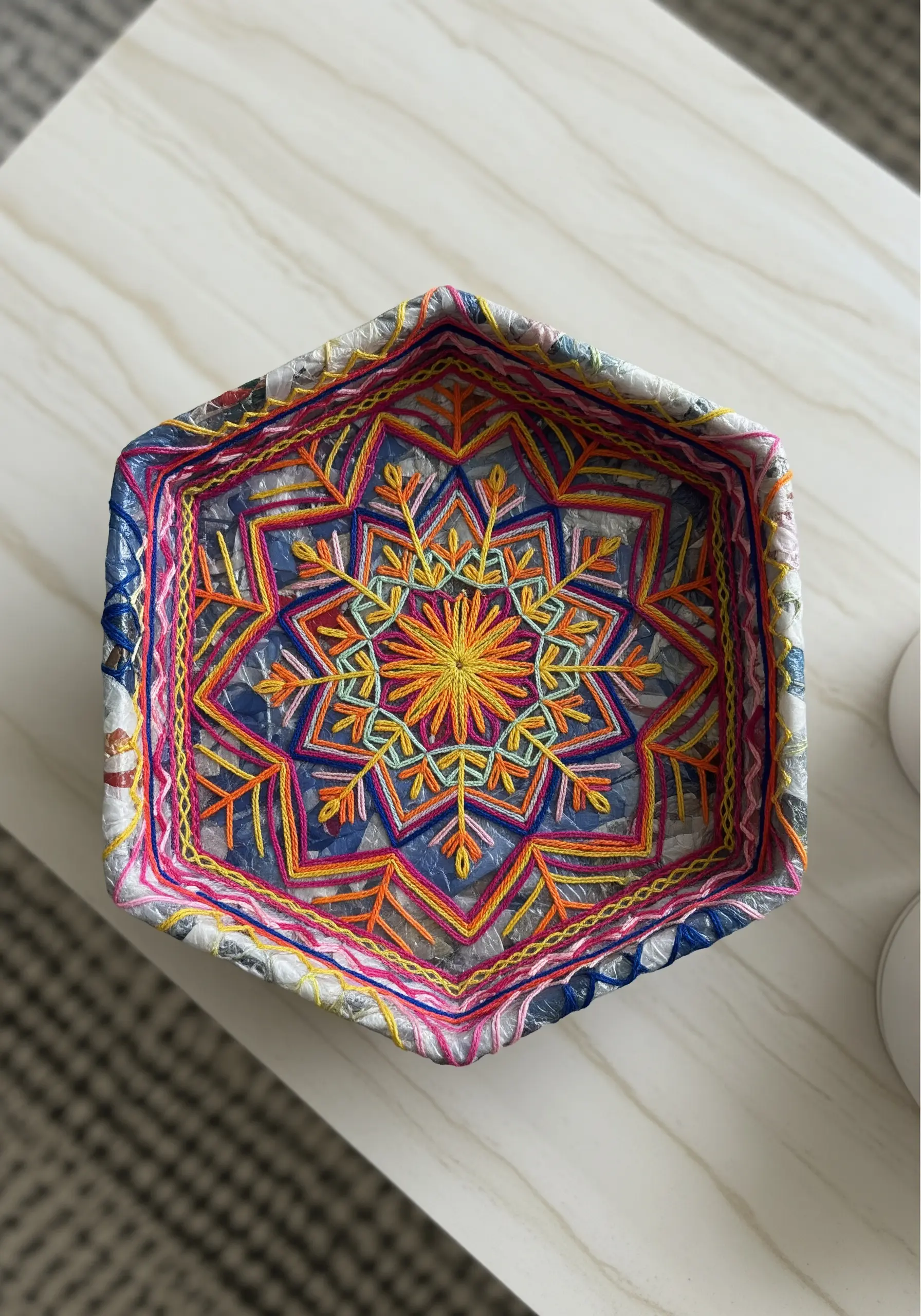 A decorative tray made from recycled plastic, embroidered with a colorful mandala pattern.