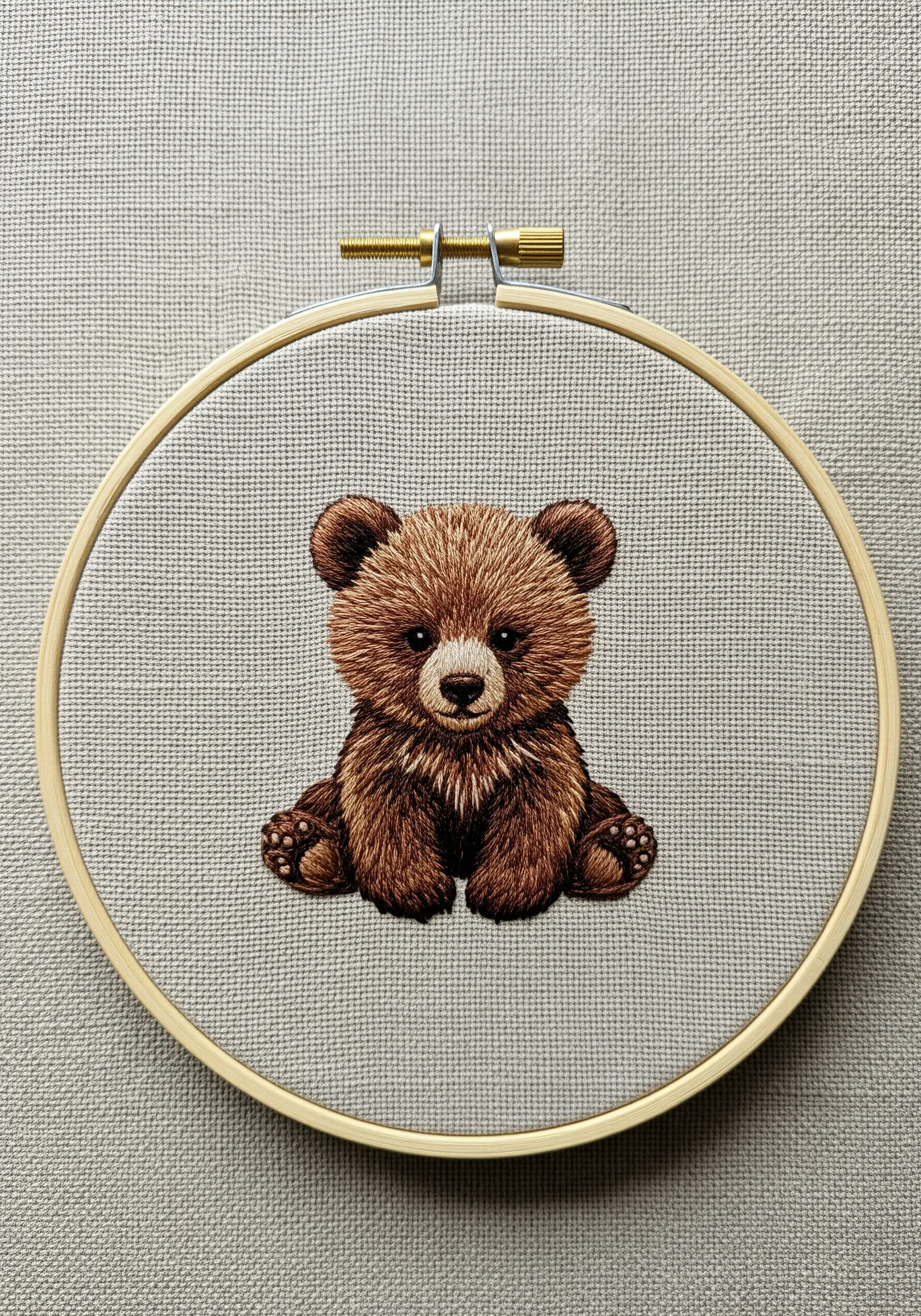 A realistic thread-painted baby bear cub with detailed fur texture in a hoop.