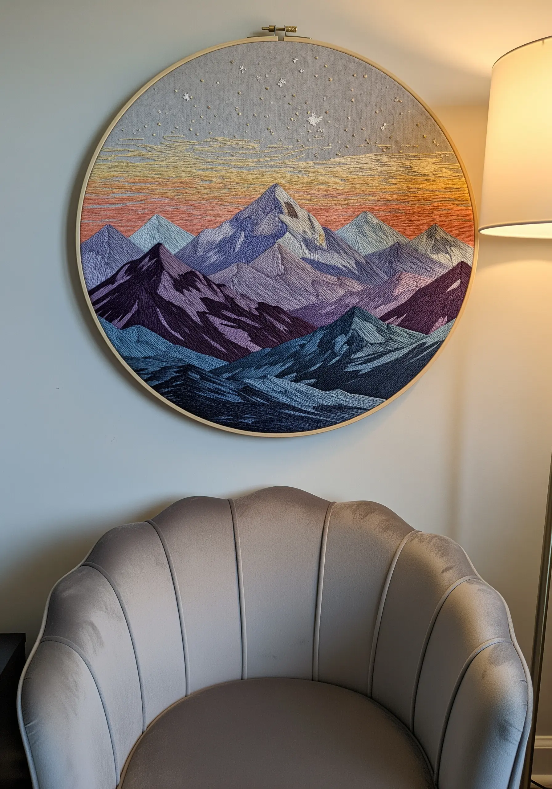 A detailed thread-painted mountain range at sunset, filling a large embroidery hoop.
