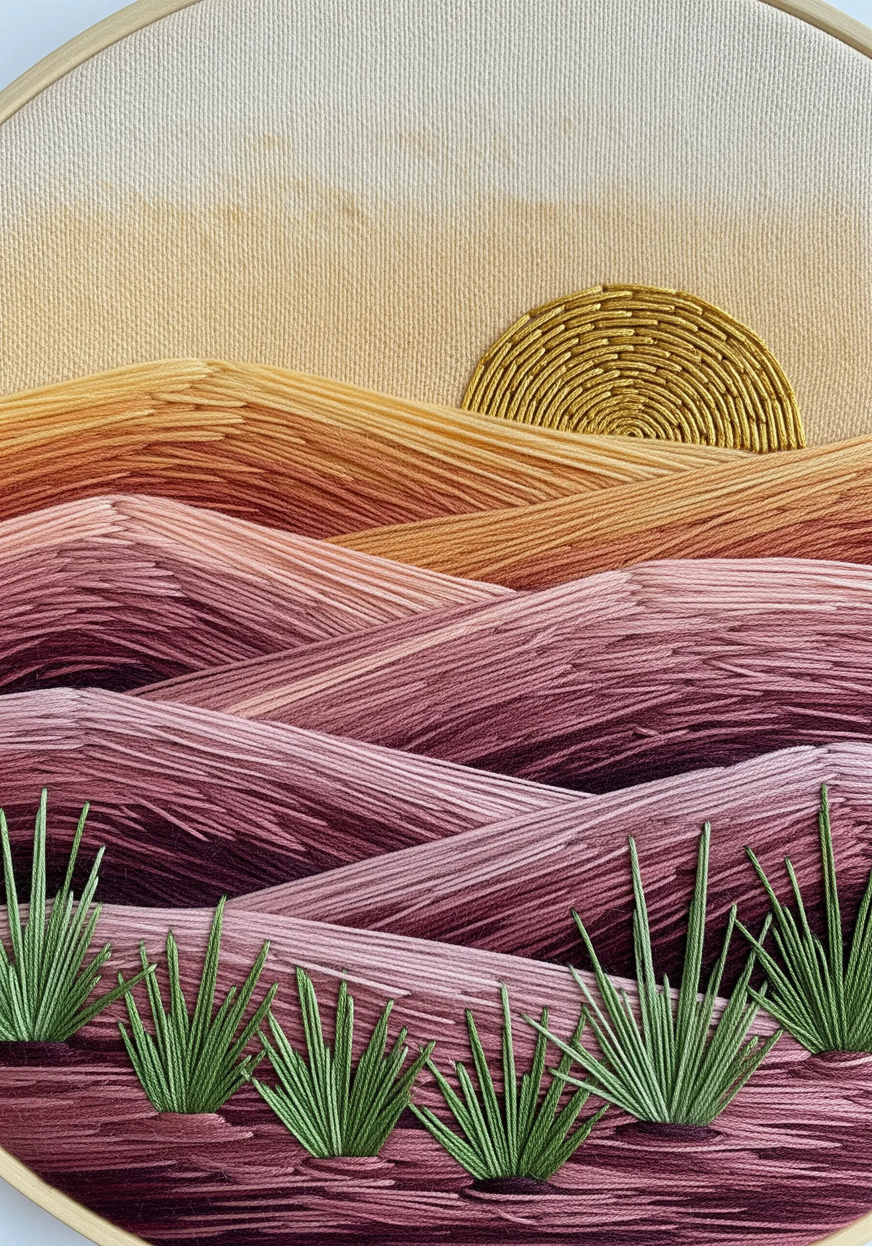 An embroidered landscape with blended long-and-short stitches creating rolling hills at sunset.