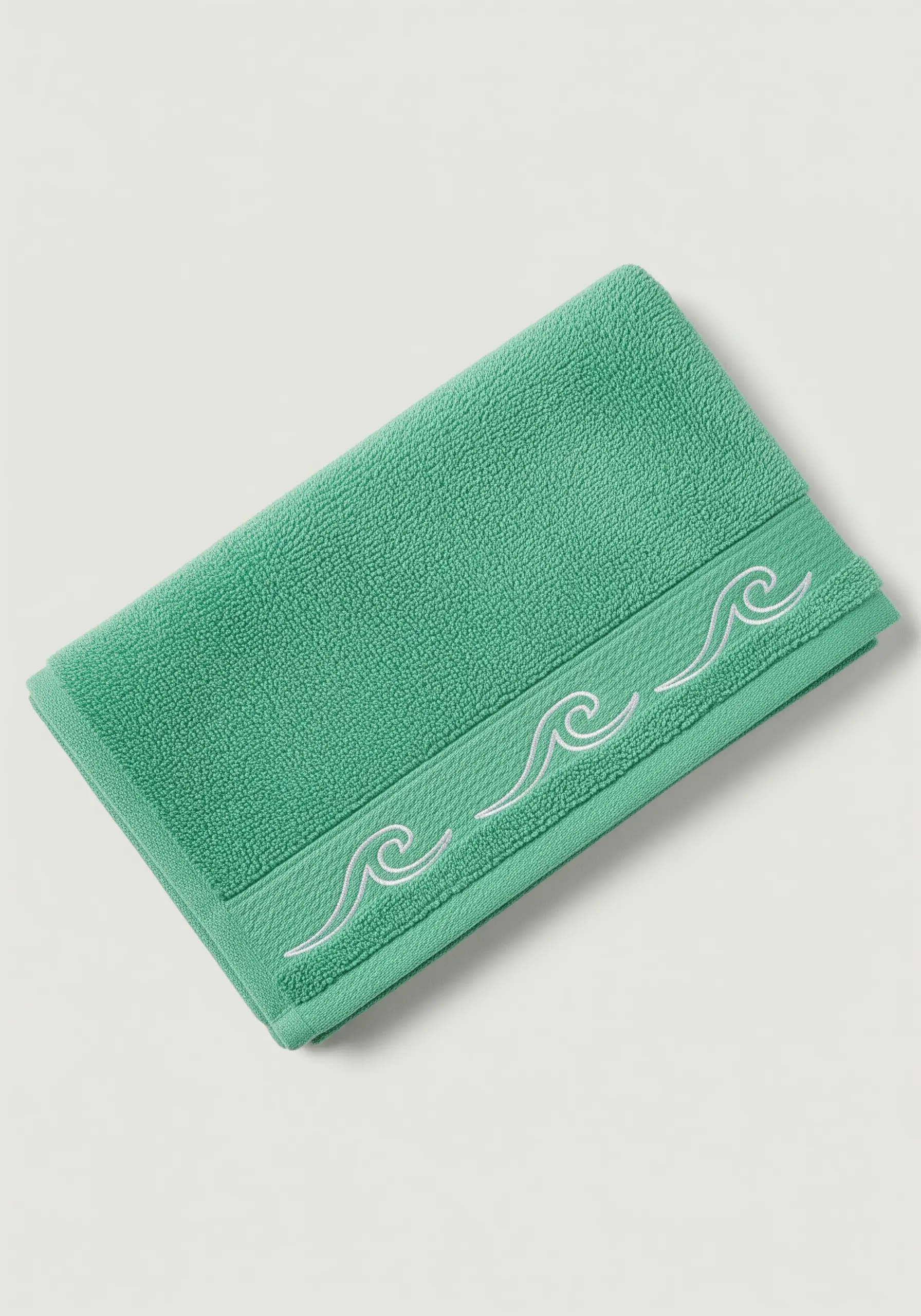 A simple white wave pattern embroidered on the border of a green terry cloth towel.