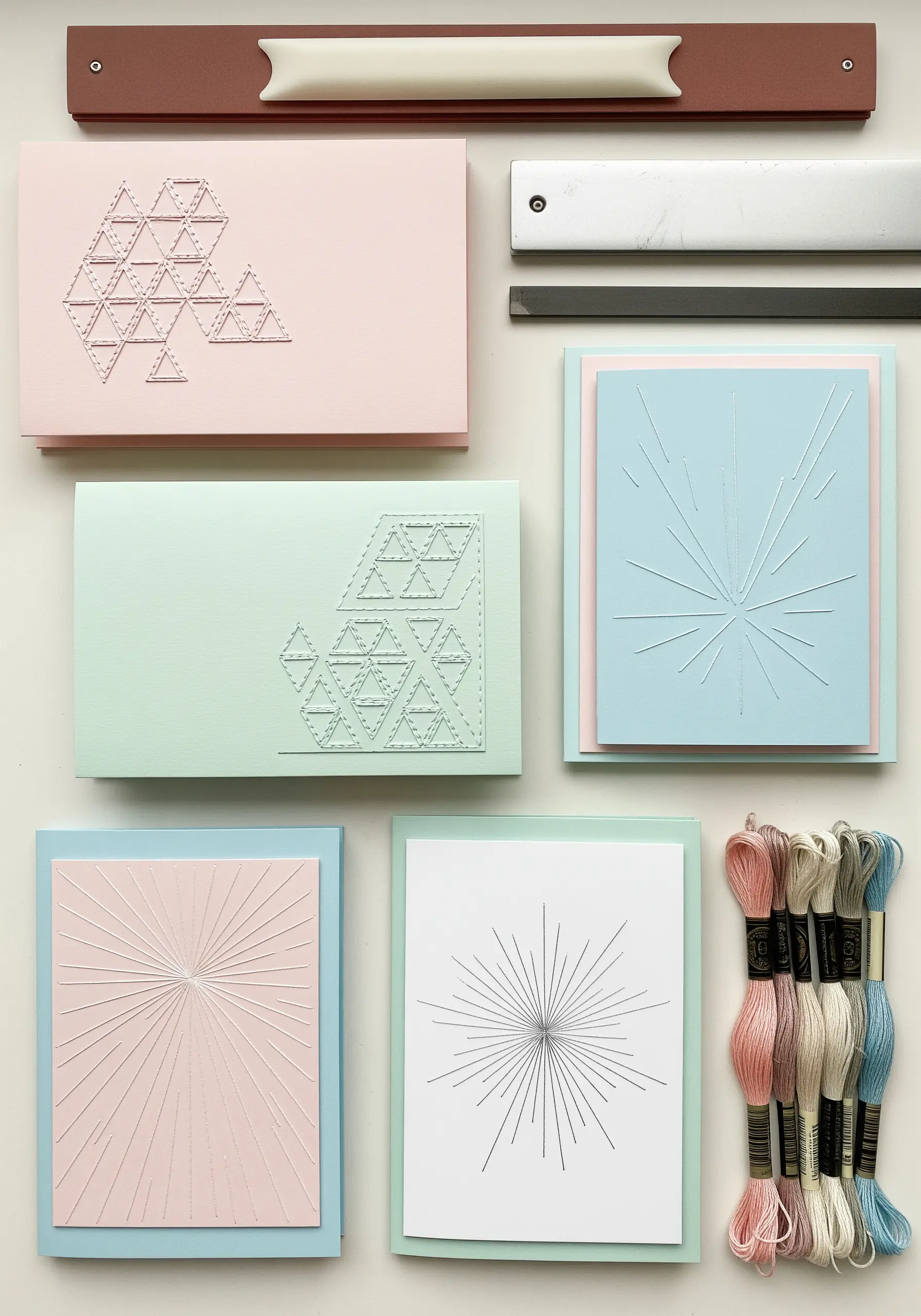 Minimalist geometric patterns stitched on pastel embossed greeting cards.