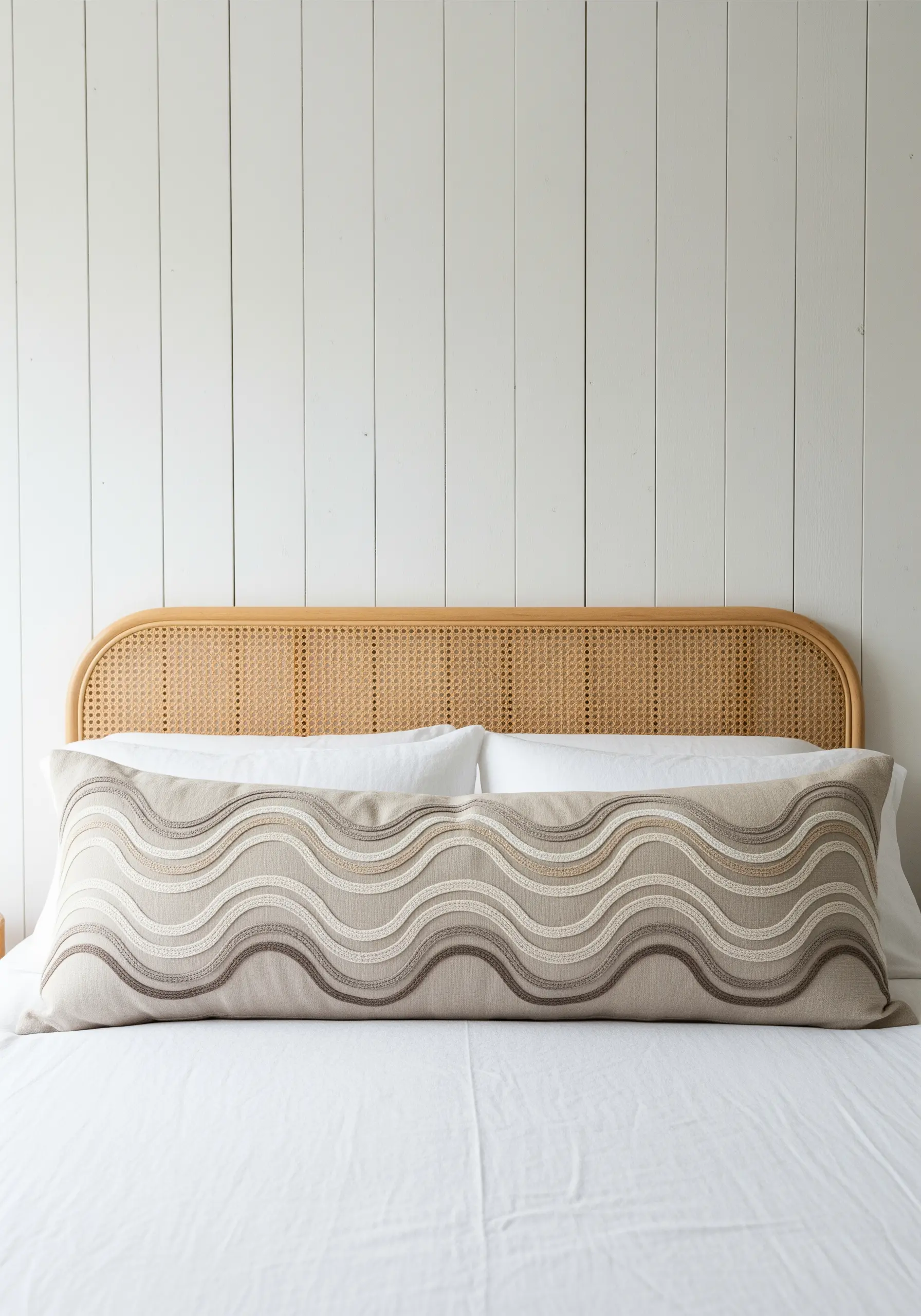 Embroidered waves in neutral color gradients on a long lumbar pillow.