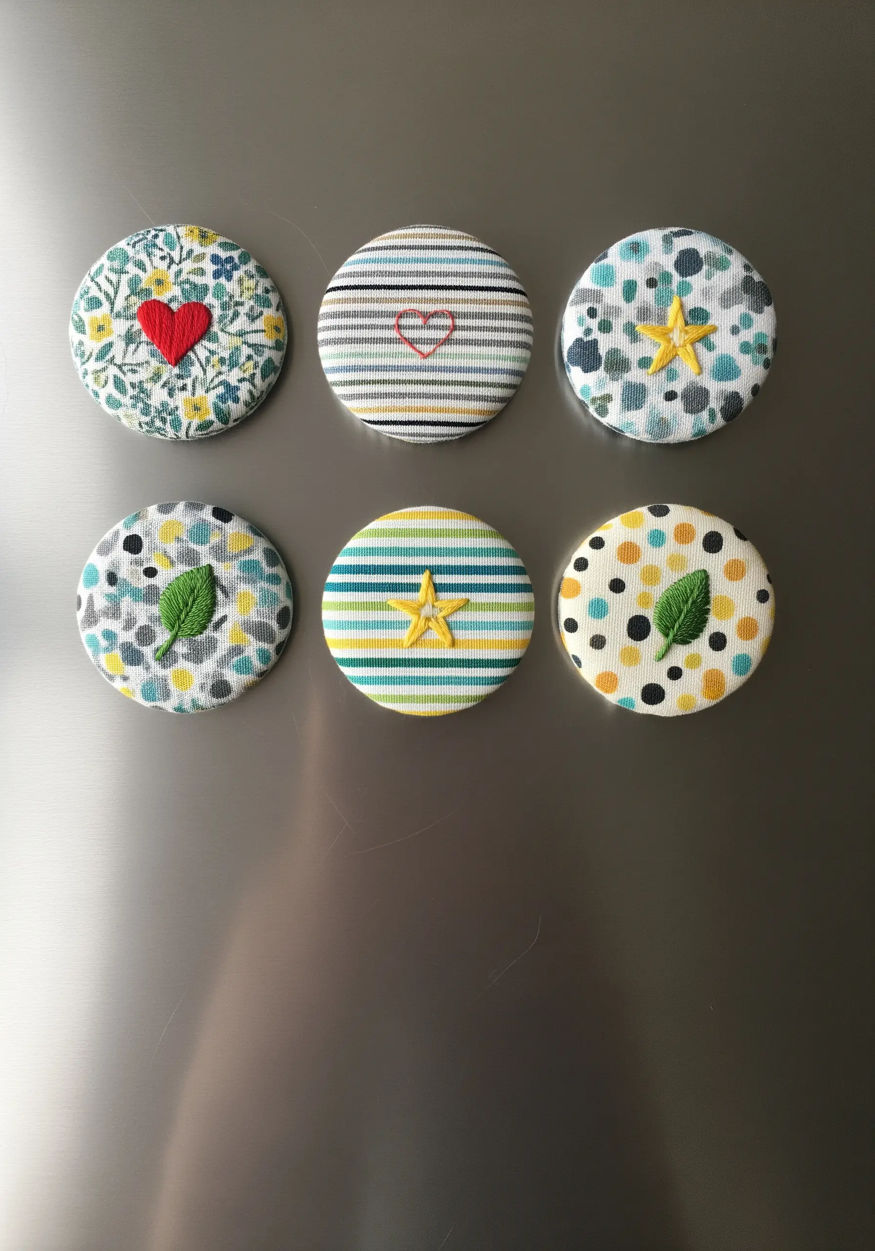 A set of six magnets made from fabric-covered buttons with tiny embroidered details.