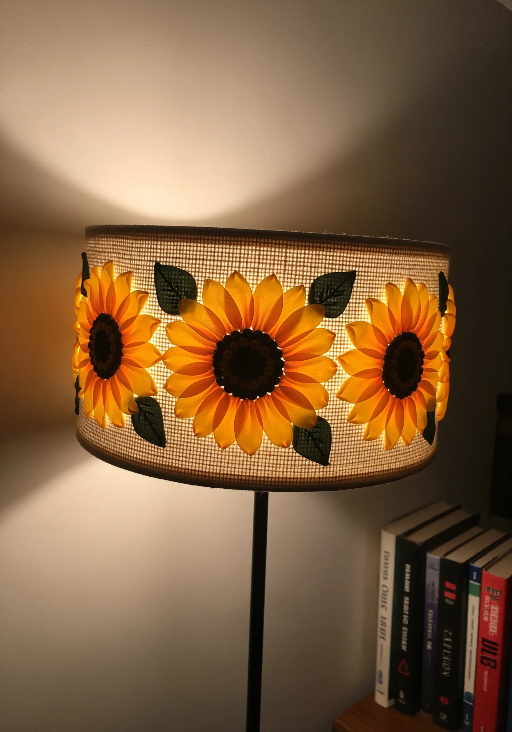 Ribbon embroidery sunflowers on a woven lampshade, glowing warmly from the light inside.