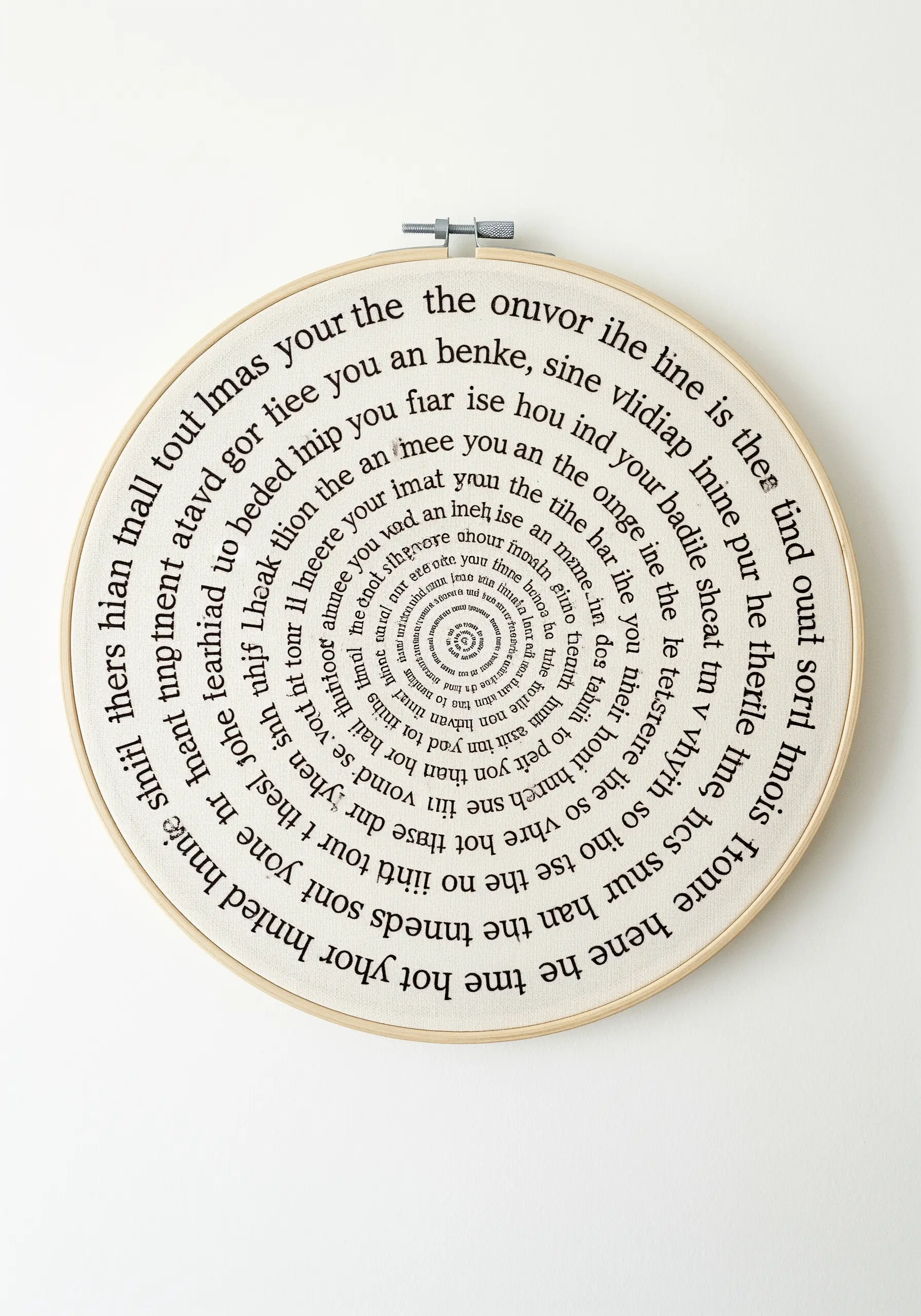 A dense spiral of tiny black text embroidered on off-white fabric in a hoop.