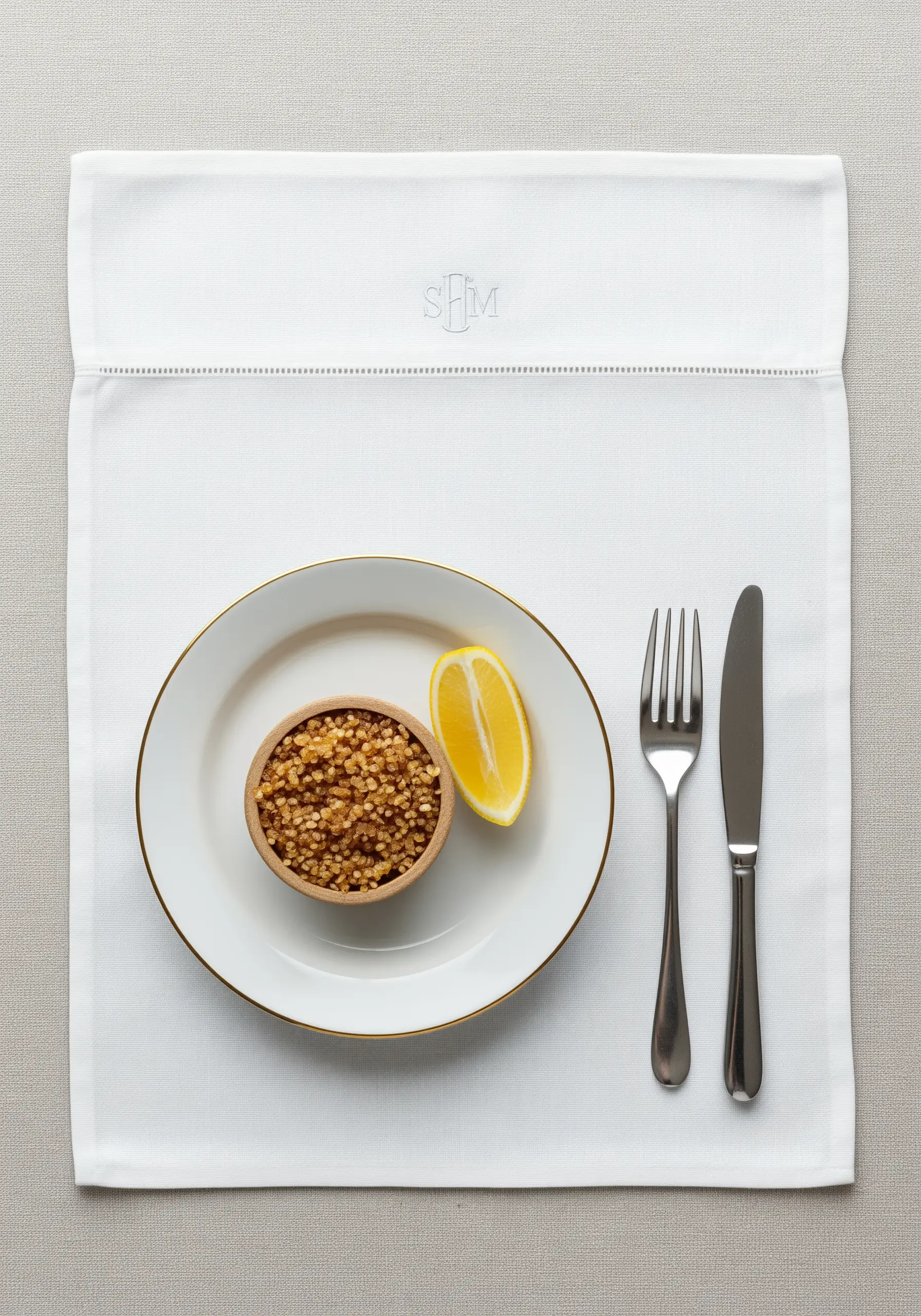 A very subtle, small, light grey 'SFM' monogram stitched on a white linen placemat.