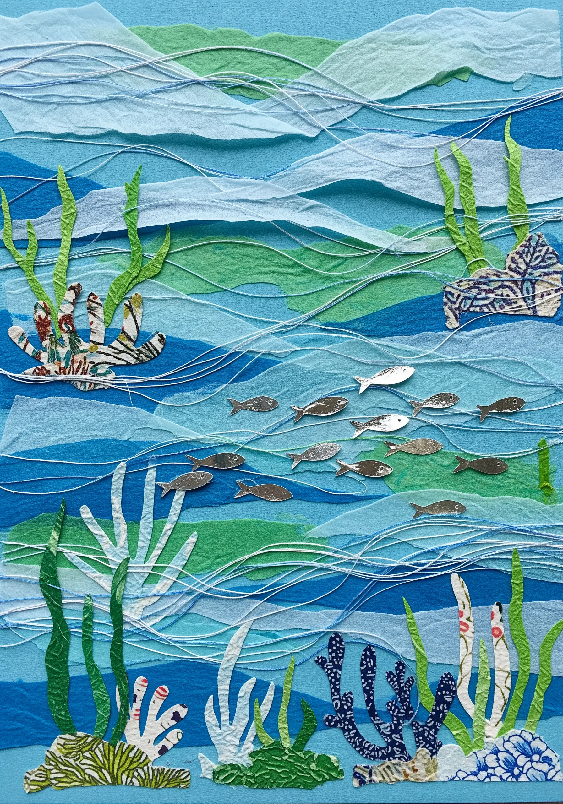 Paper collage of an underwater scene with white thread stitched as water currents.
