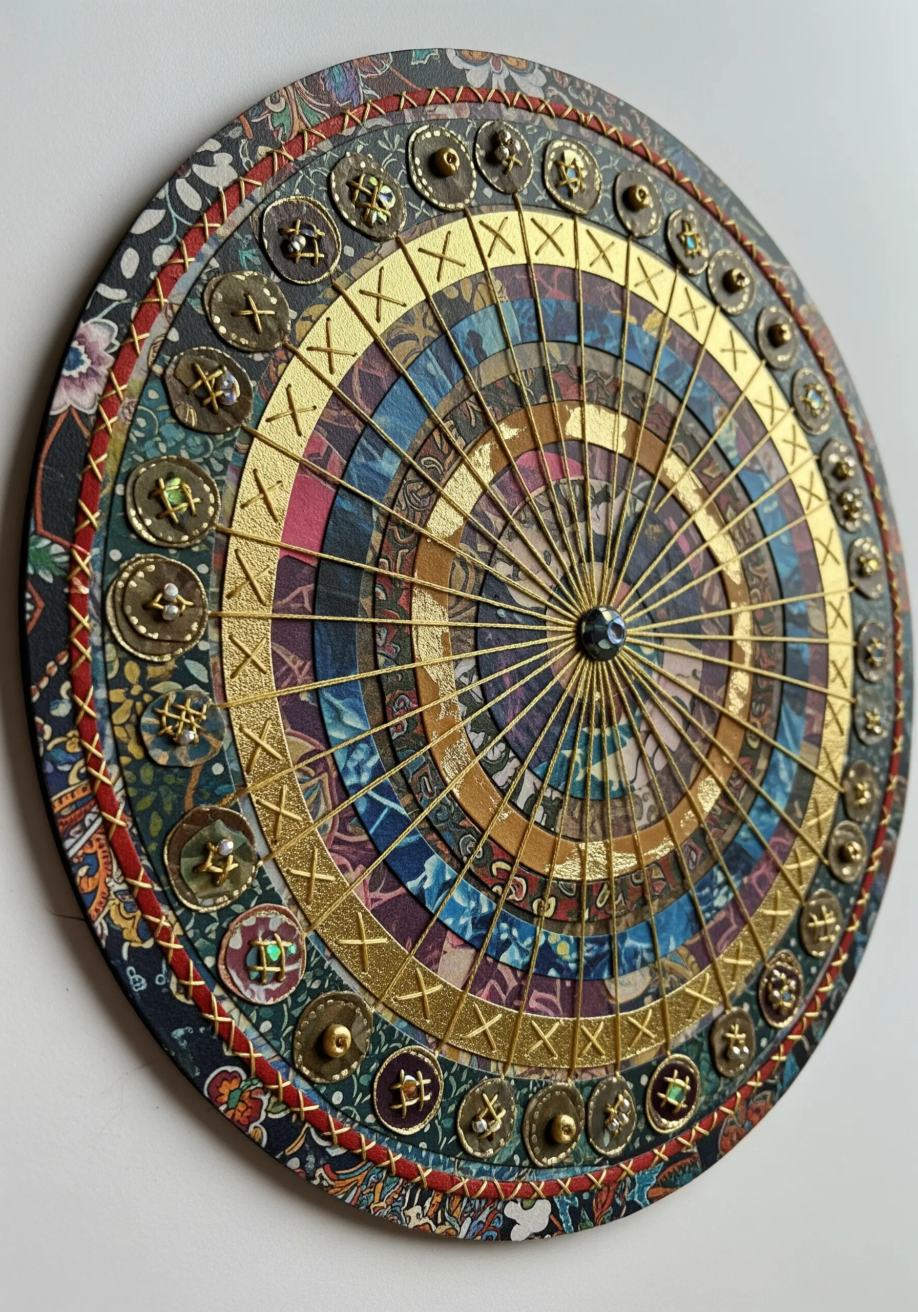 A circular collage with multiple patterns unified by radiating gold thread stitches.