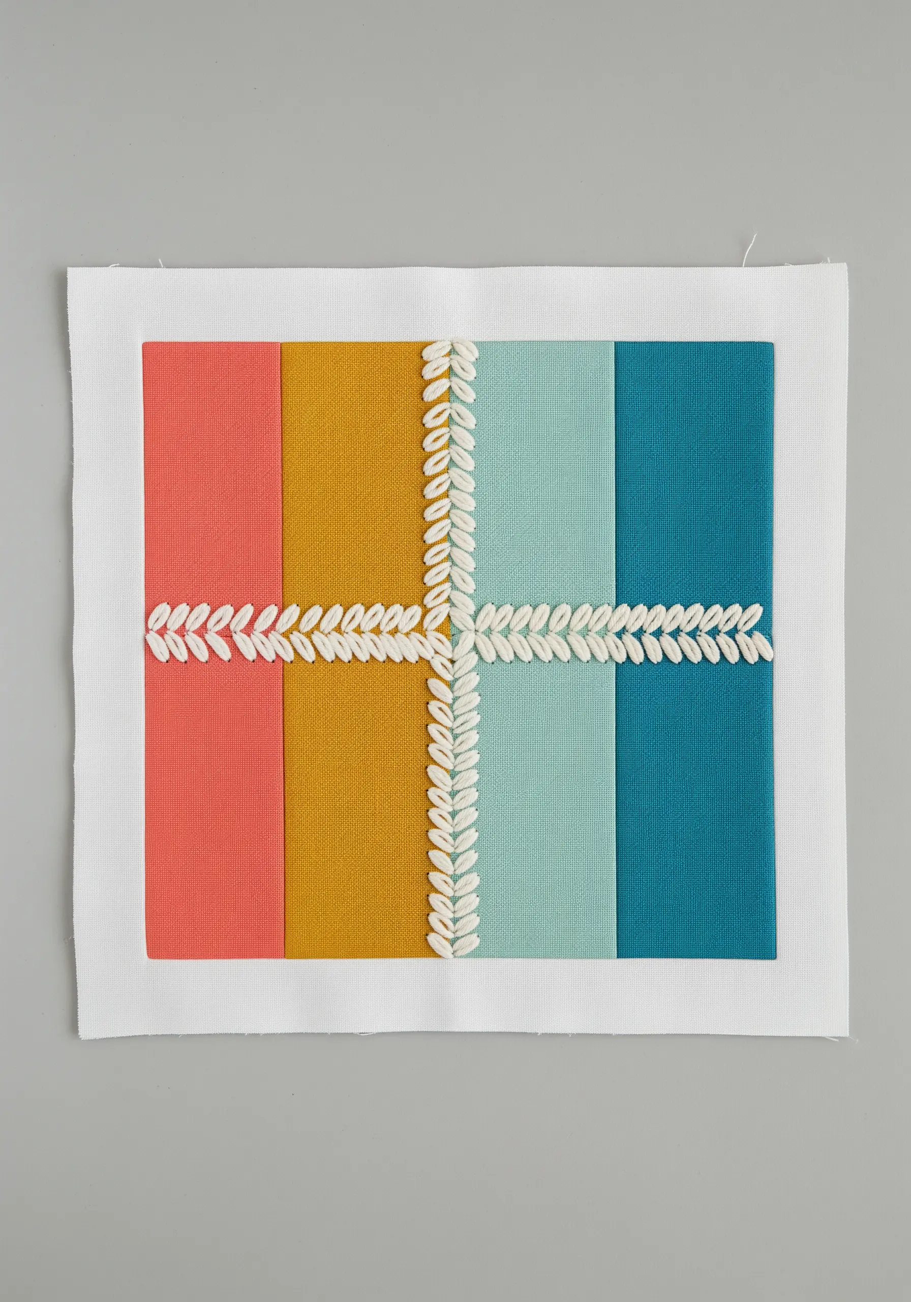 Four vertical color blocks of fabric joined by a central white fern stitch detail.