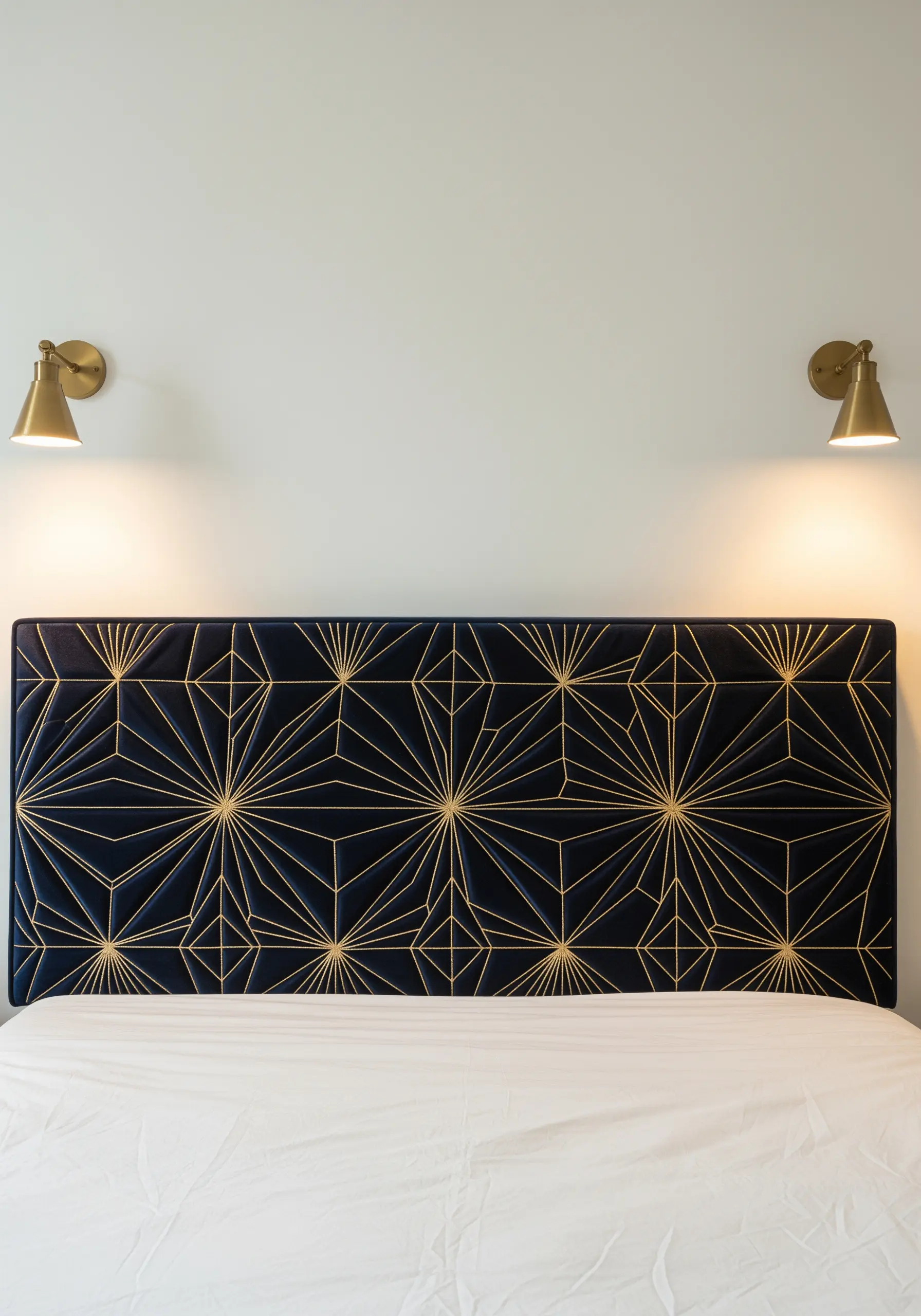 Geometric gold lines embroidered on a dark blue velvet upholstered headboard.