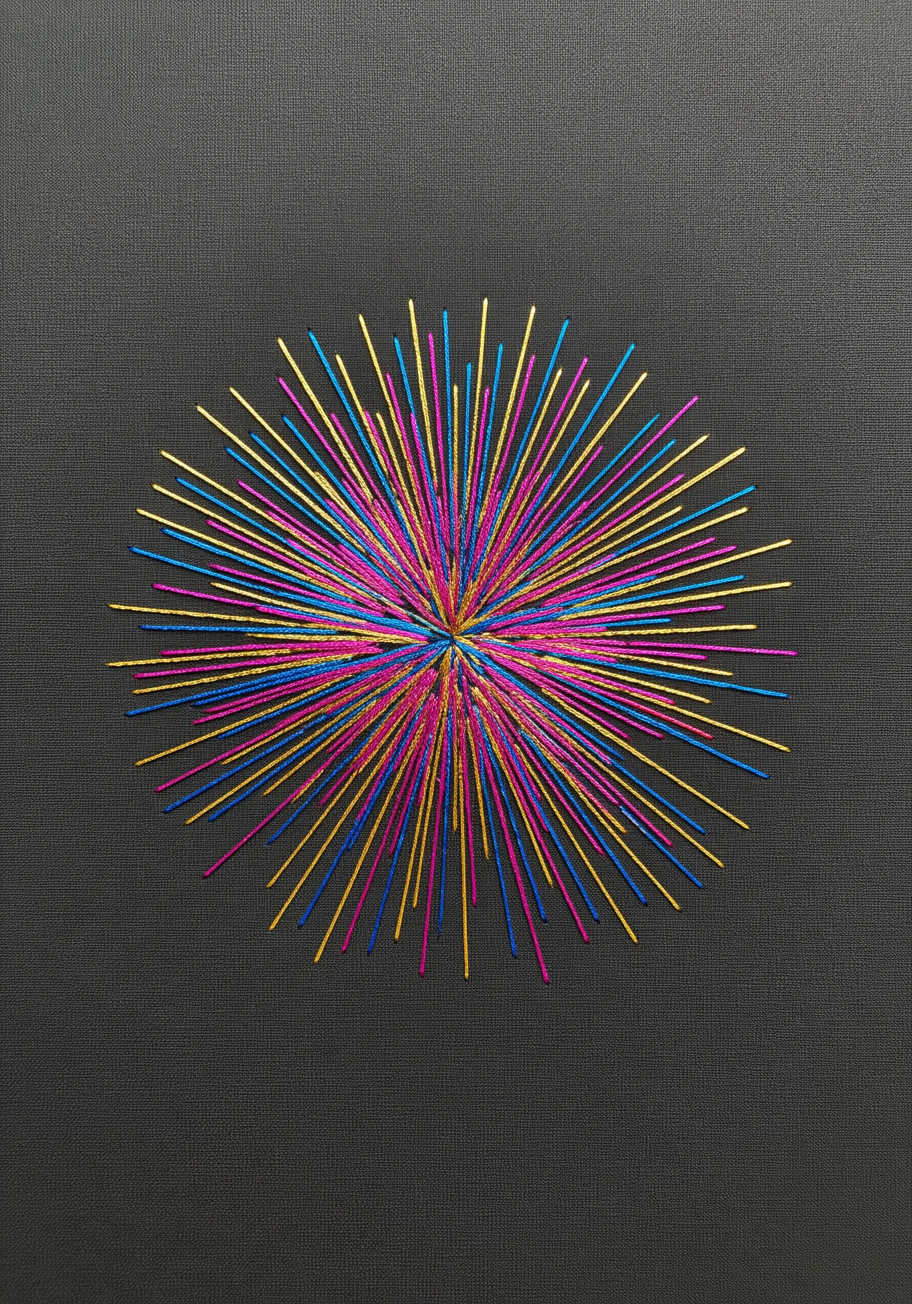 A starburst embroidery using only cyan, magenta, yellow, and black threads.