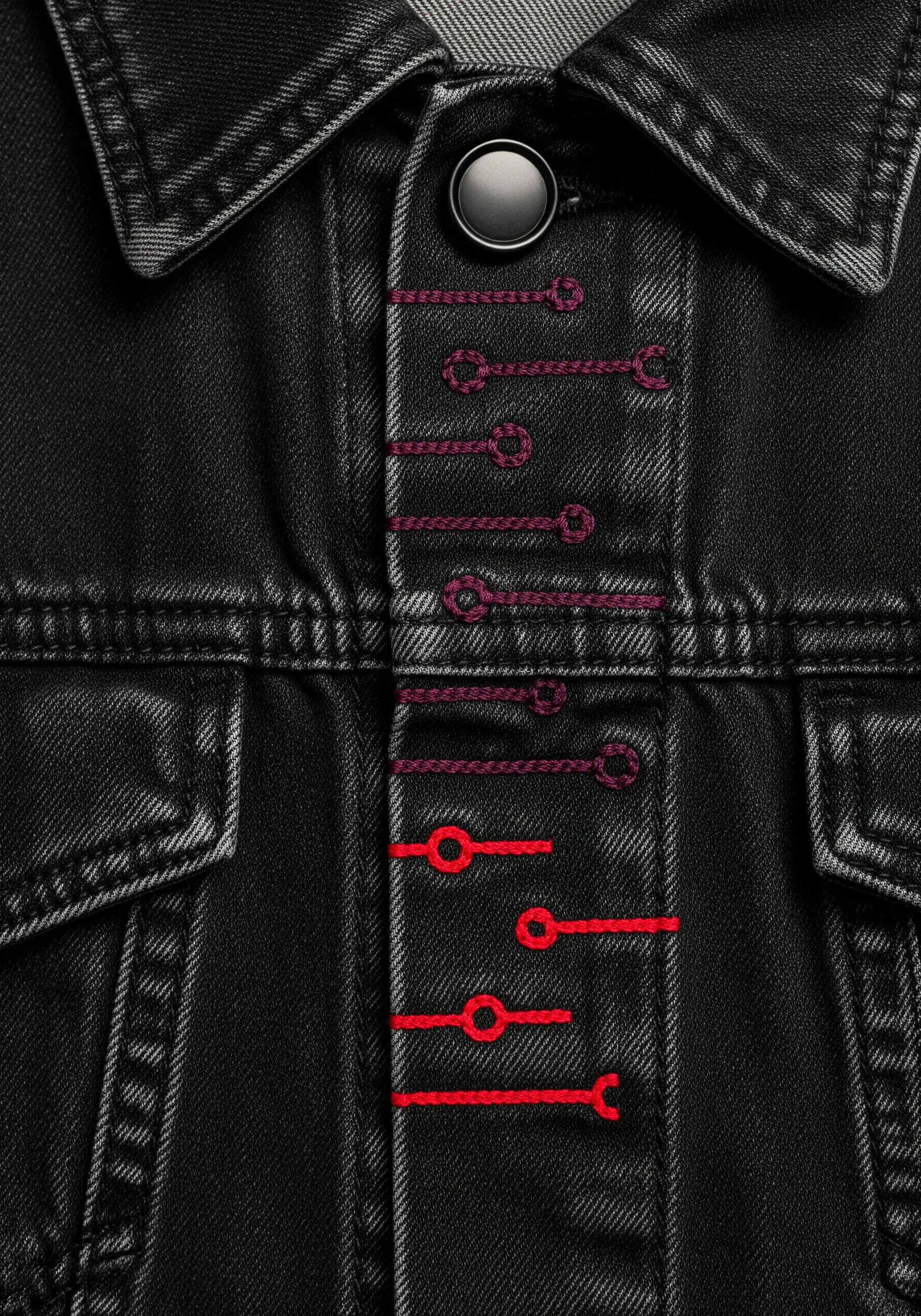 Decorative buttonhole stitches in a red-to-purple gradient along the placket of a black denim jacket.