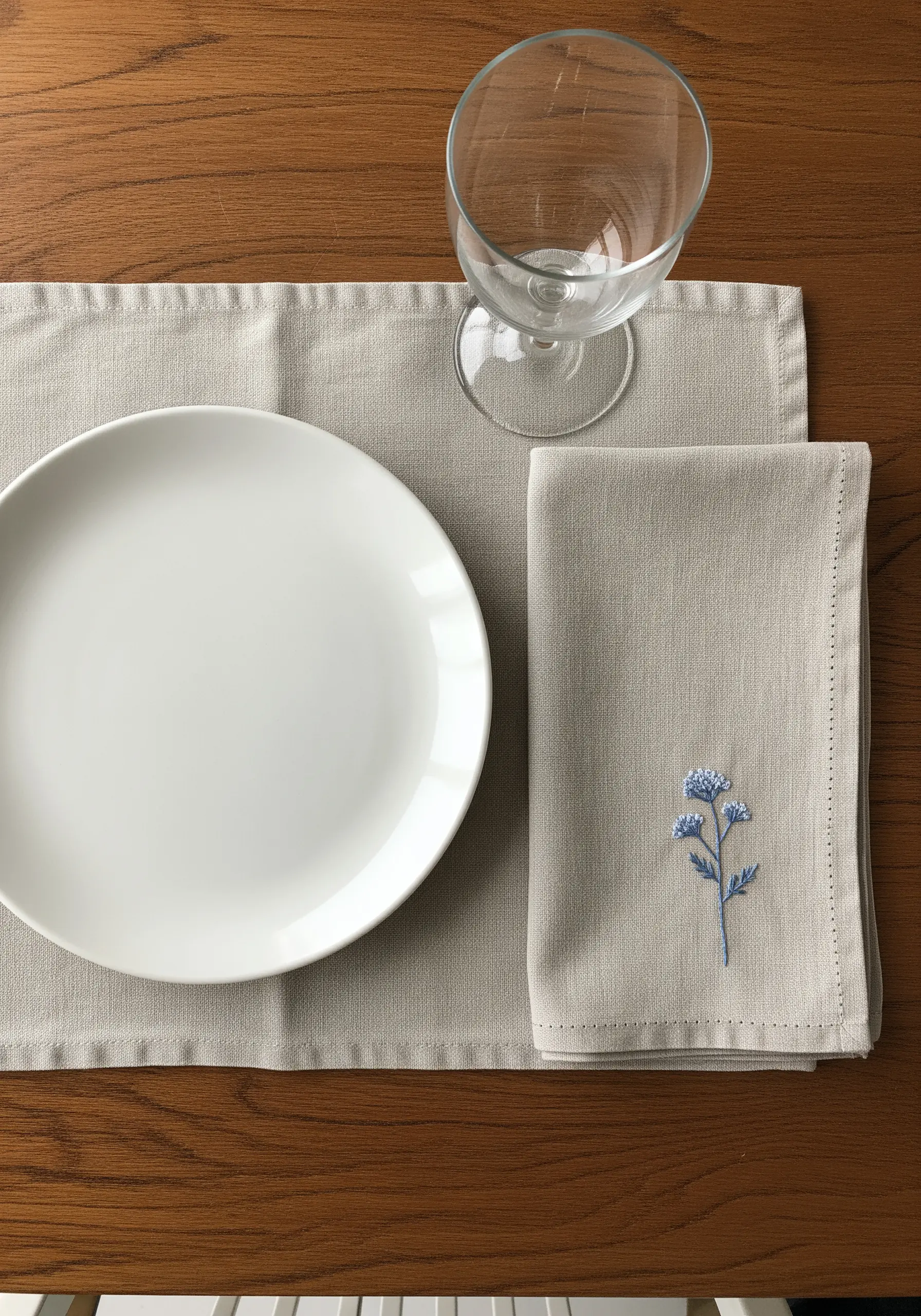 A small blue wildflower embroidered on the corner of a linen napkin using French knots.