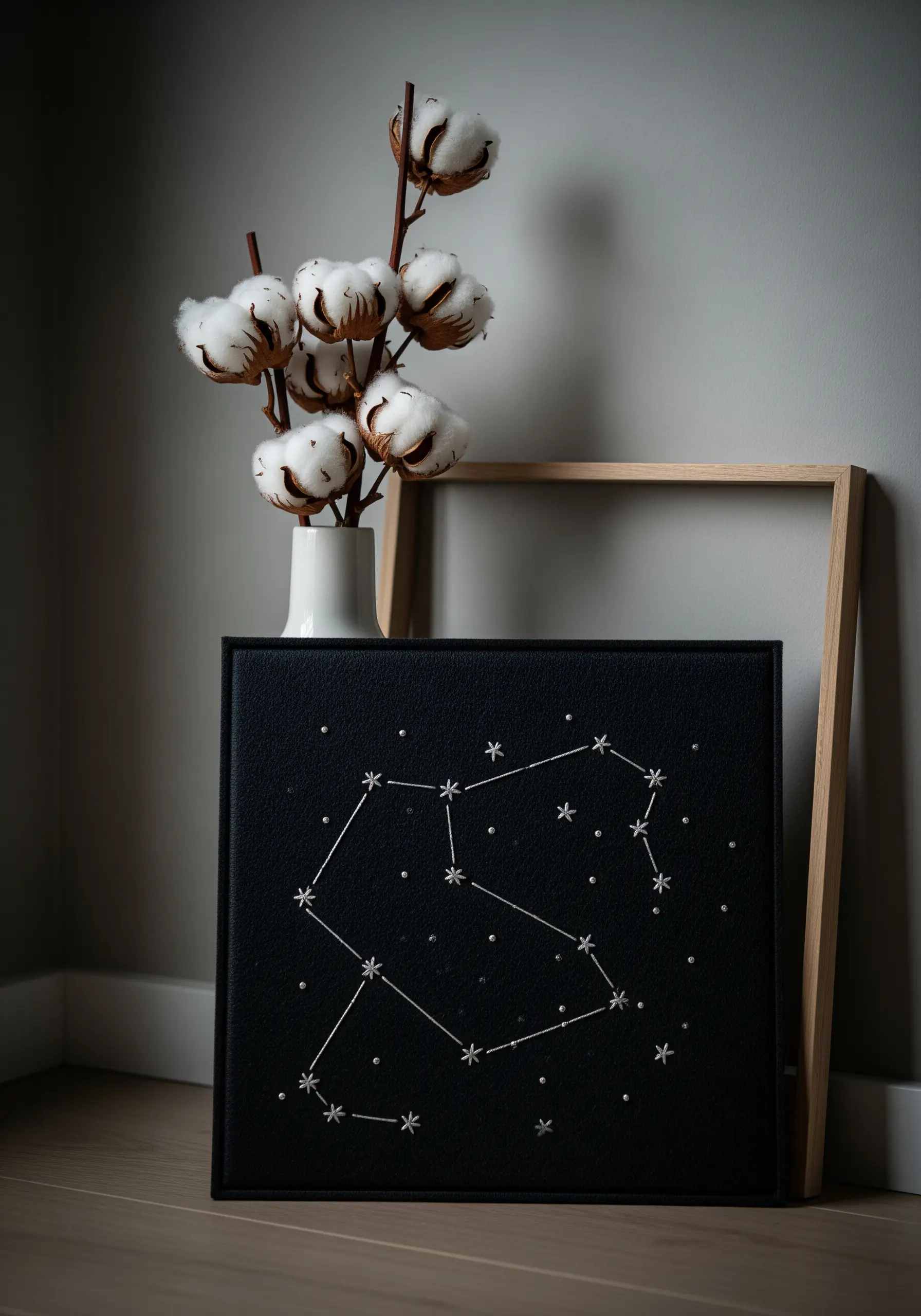 A star constellation stitched in white thread with small beads on a black canvas.