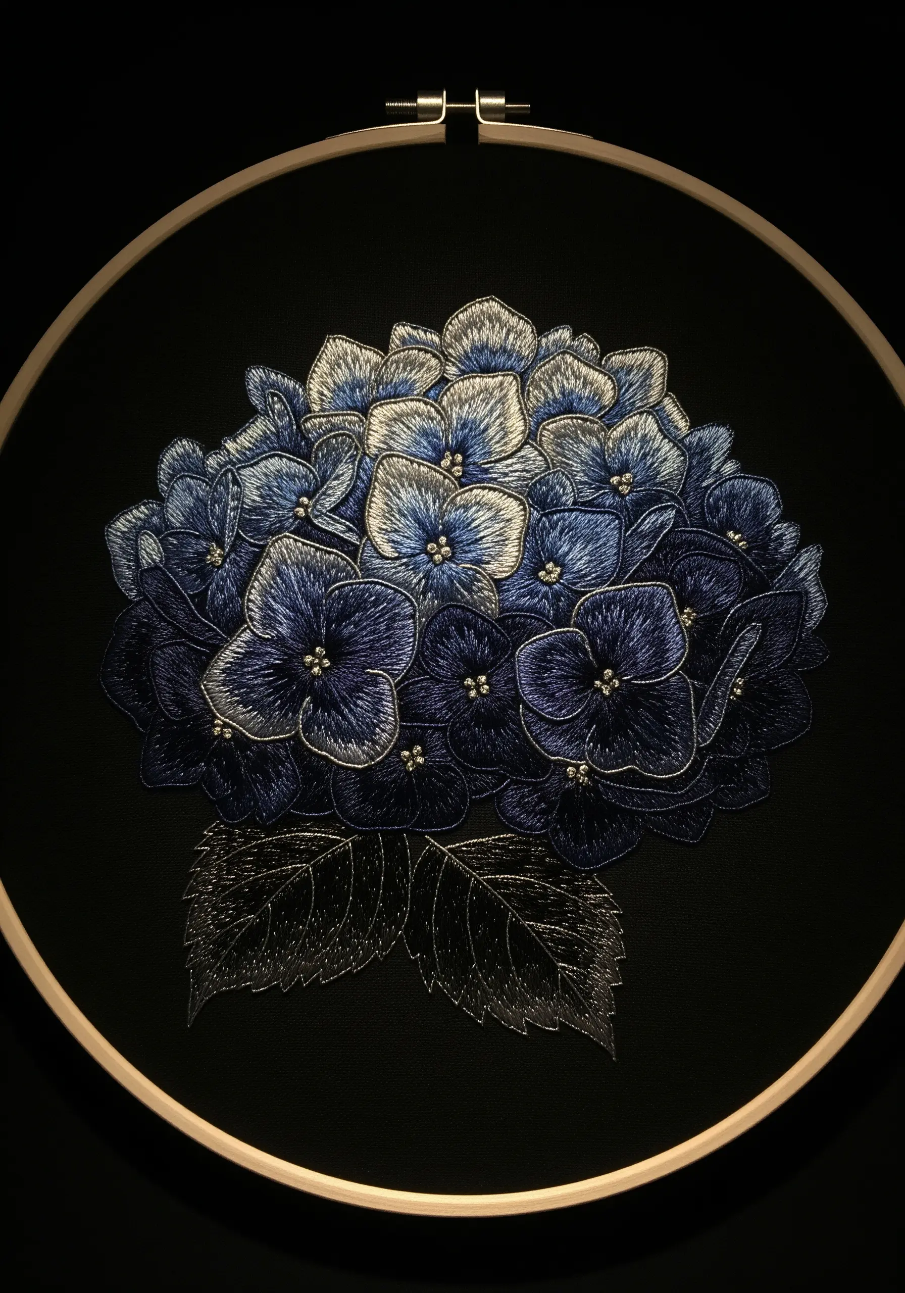 Blue hydrangea on black fabric, with silver metallic thread outlining the petals.