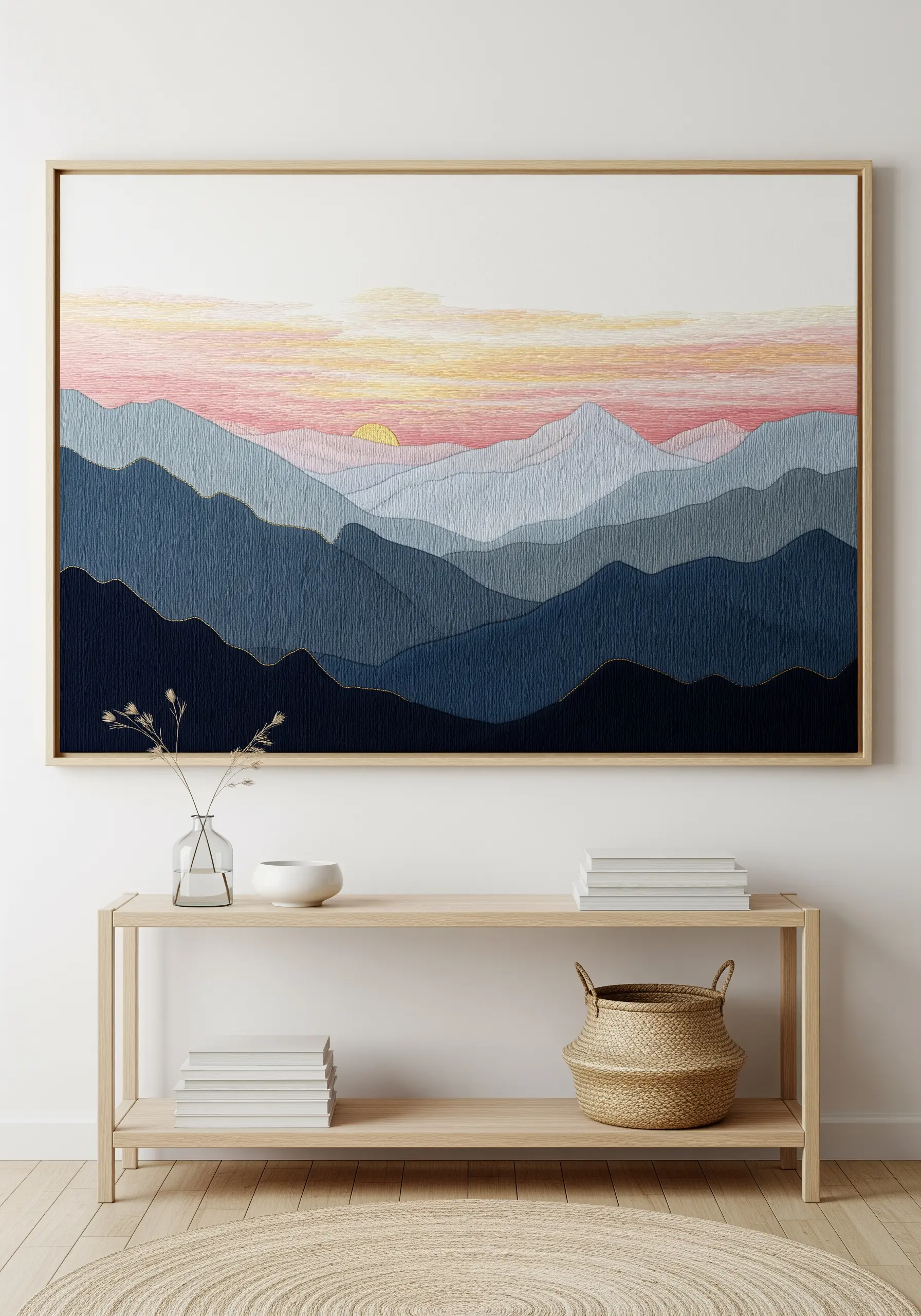 Large framed embroidery of layered blue mountains with a pink sunset and gold outlines.