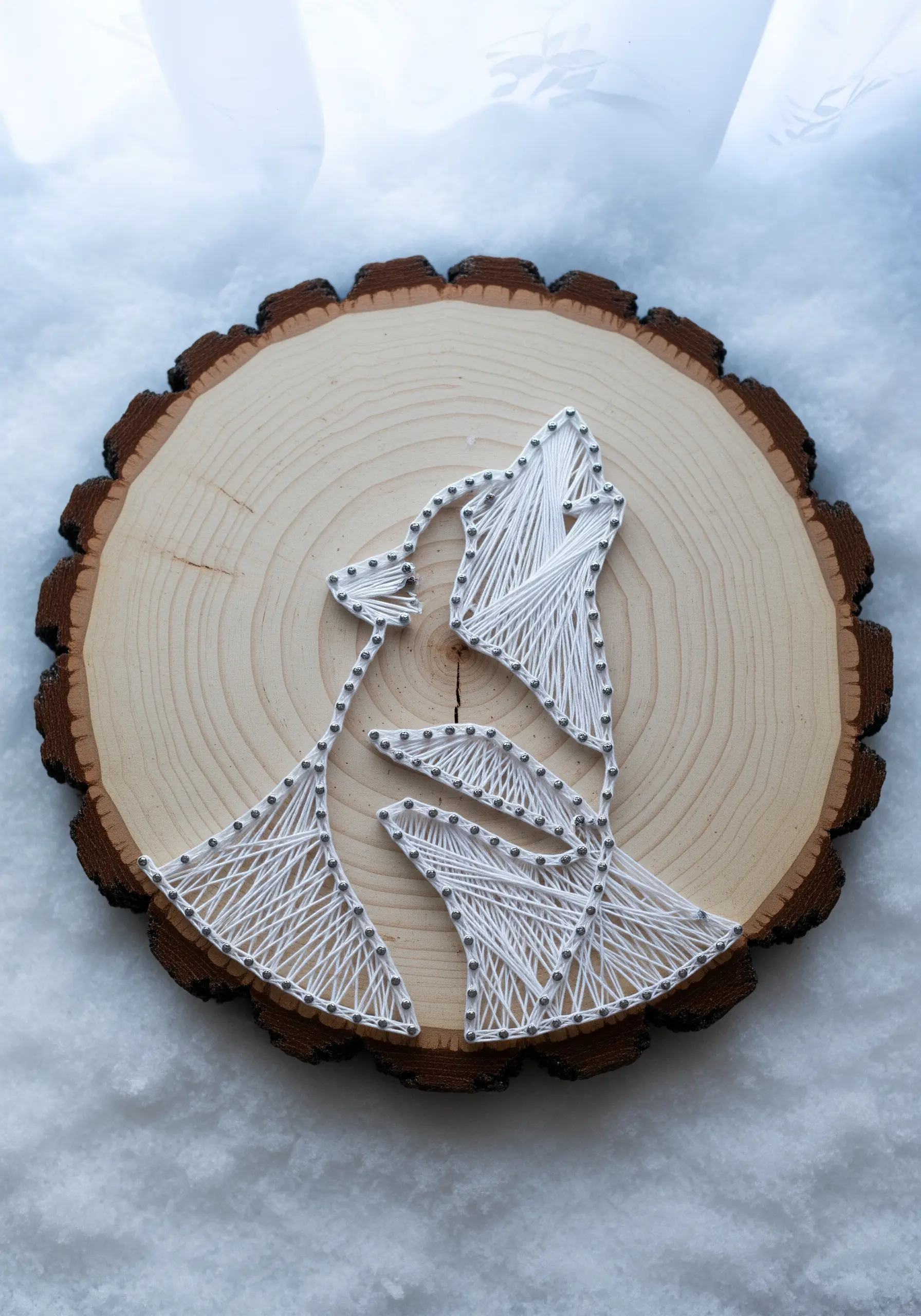 Minimalist string art of a howling wolf on a natural wood slice.