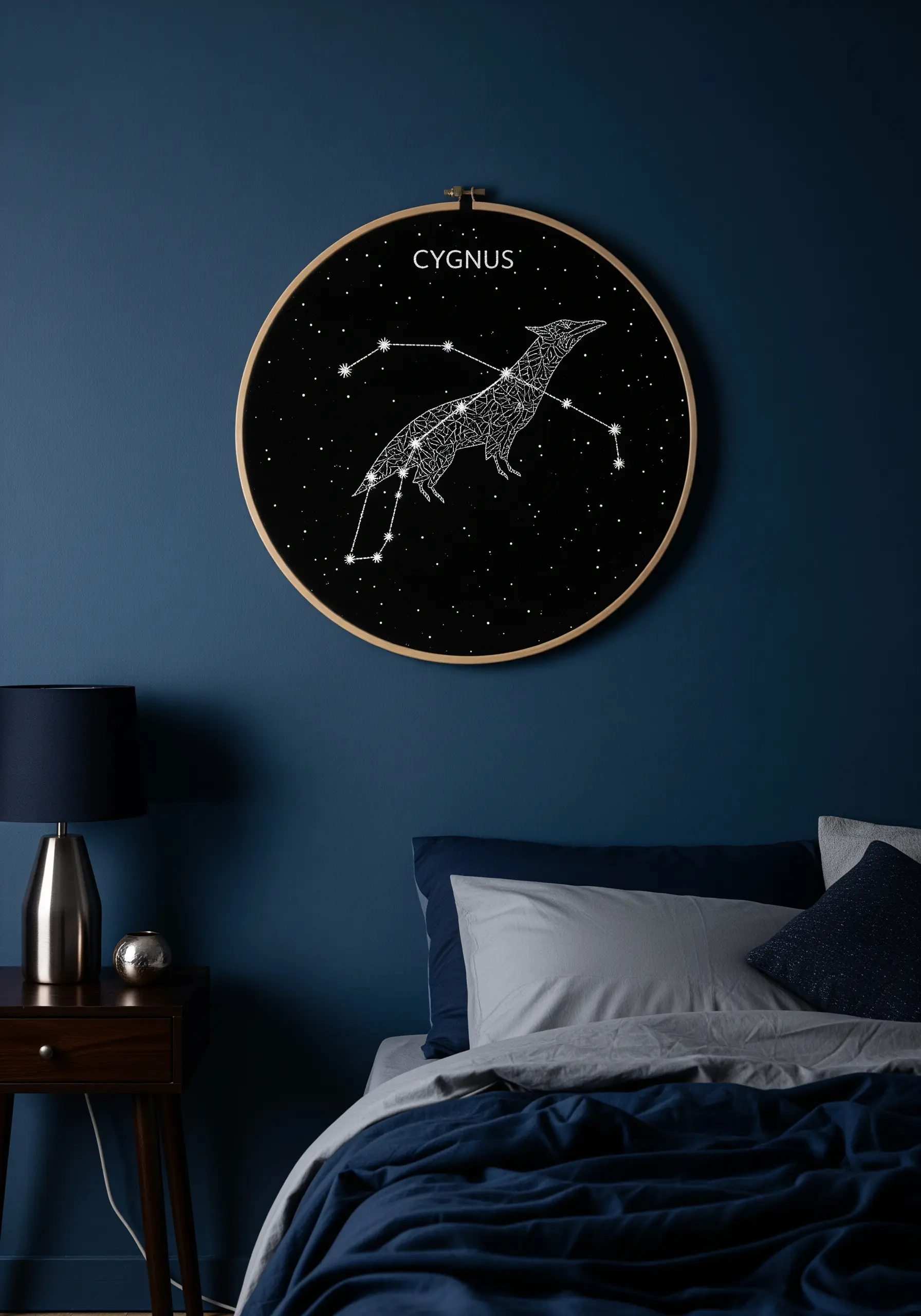 A Cygnus constellation stitched in white thread on black fabric inside an embroidery hoop.