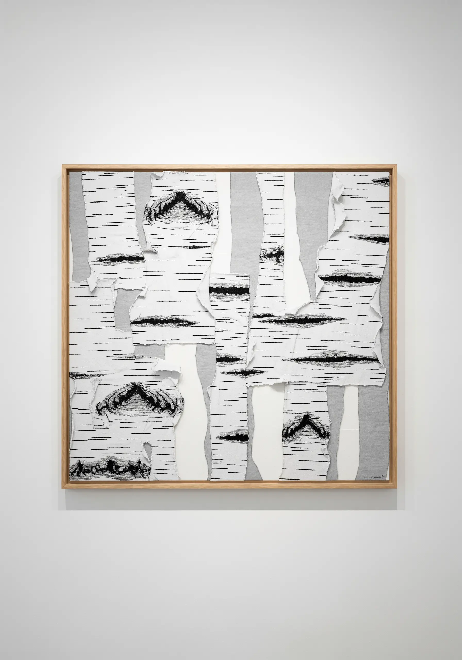 A framed fabric collage of birch tree bark using torn, stitched white fabric on gray.