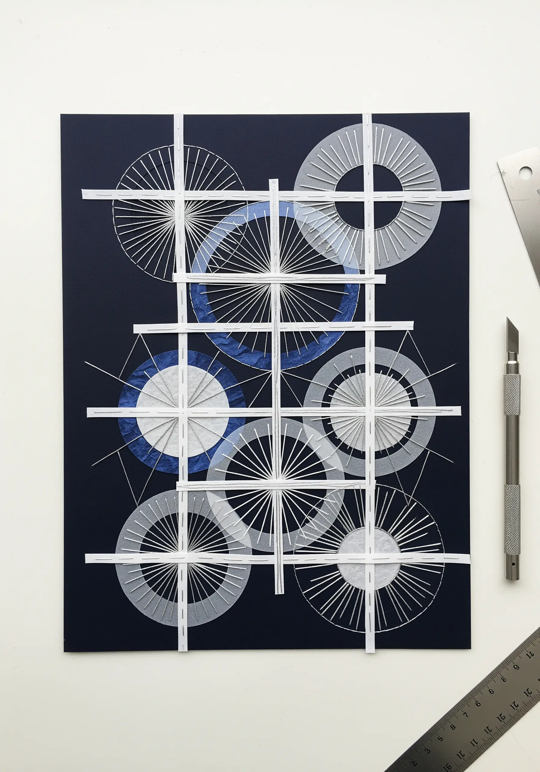 Geometric composition with layered circles made of paper strips and thread-like lines.