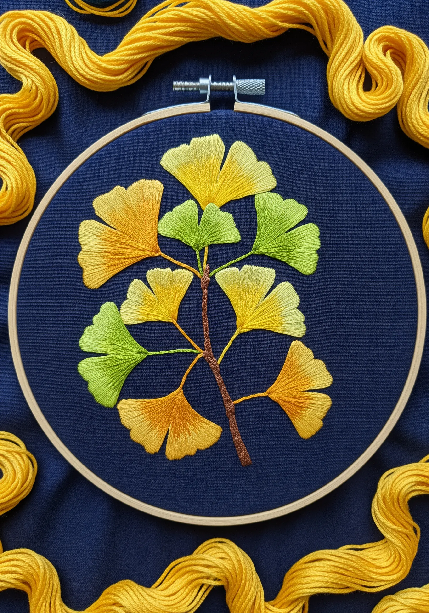 A branch of ginkgo leaves with yellow-to-green gradients on dark blue fabric.