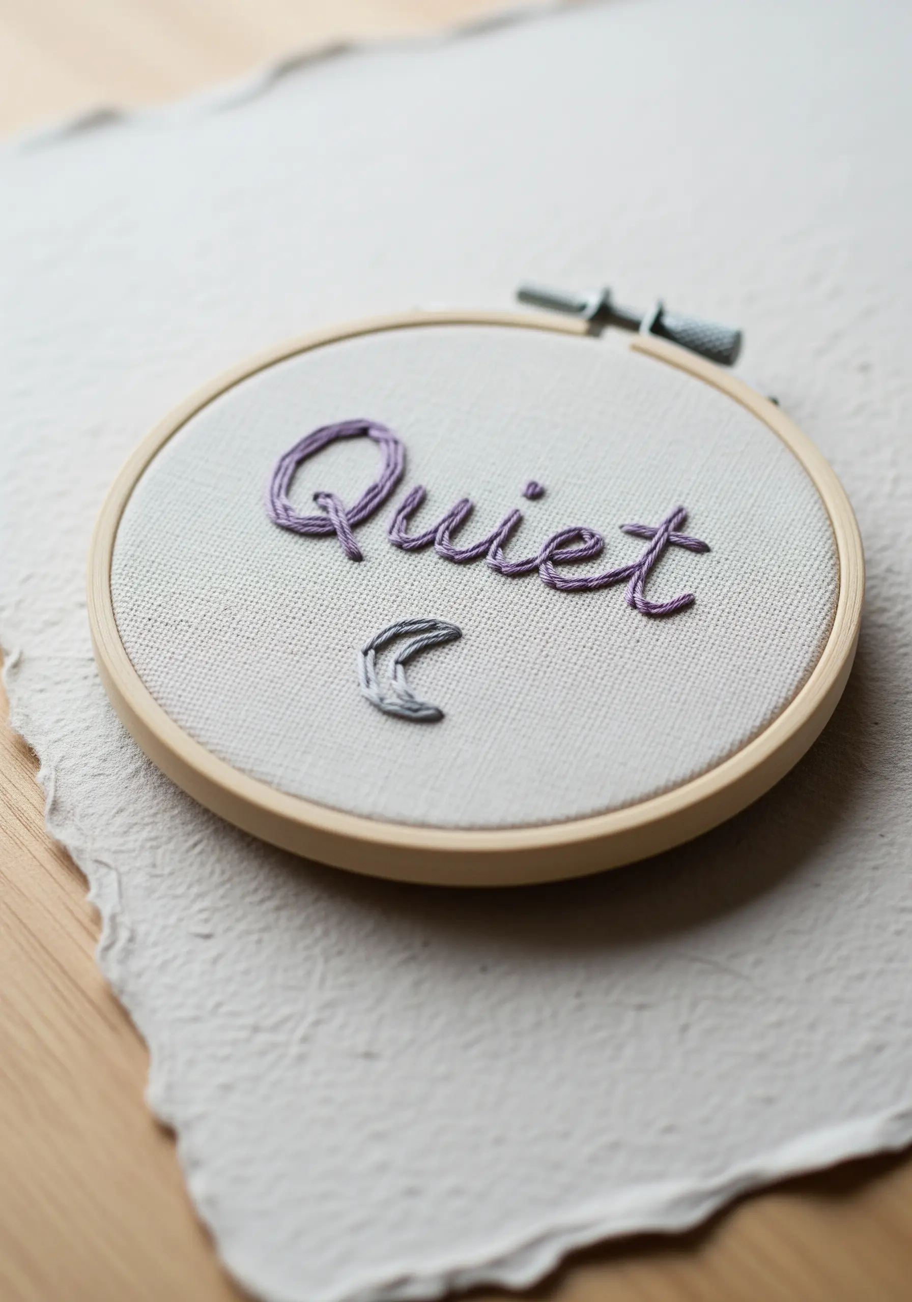 'Quiet' stitched in variegated purple thread with a small crescent moon.