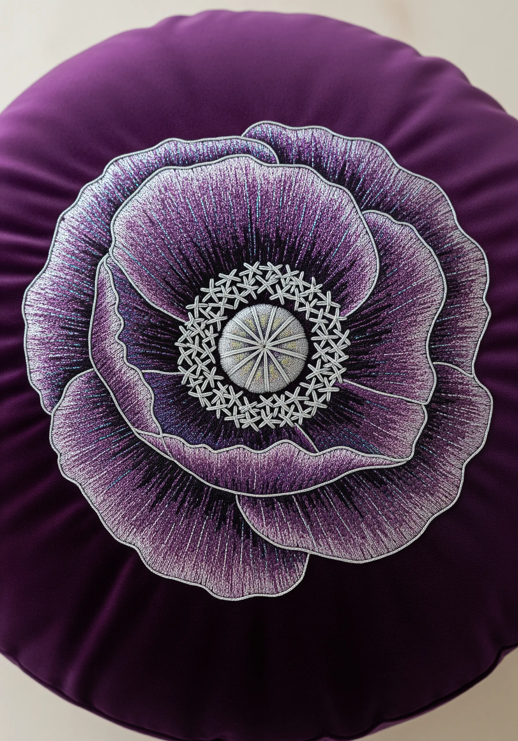 A highly detailed purple poppy embroidered on a round purple velvet cushion.