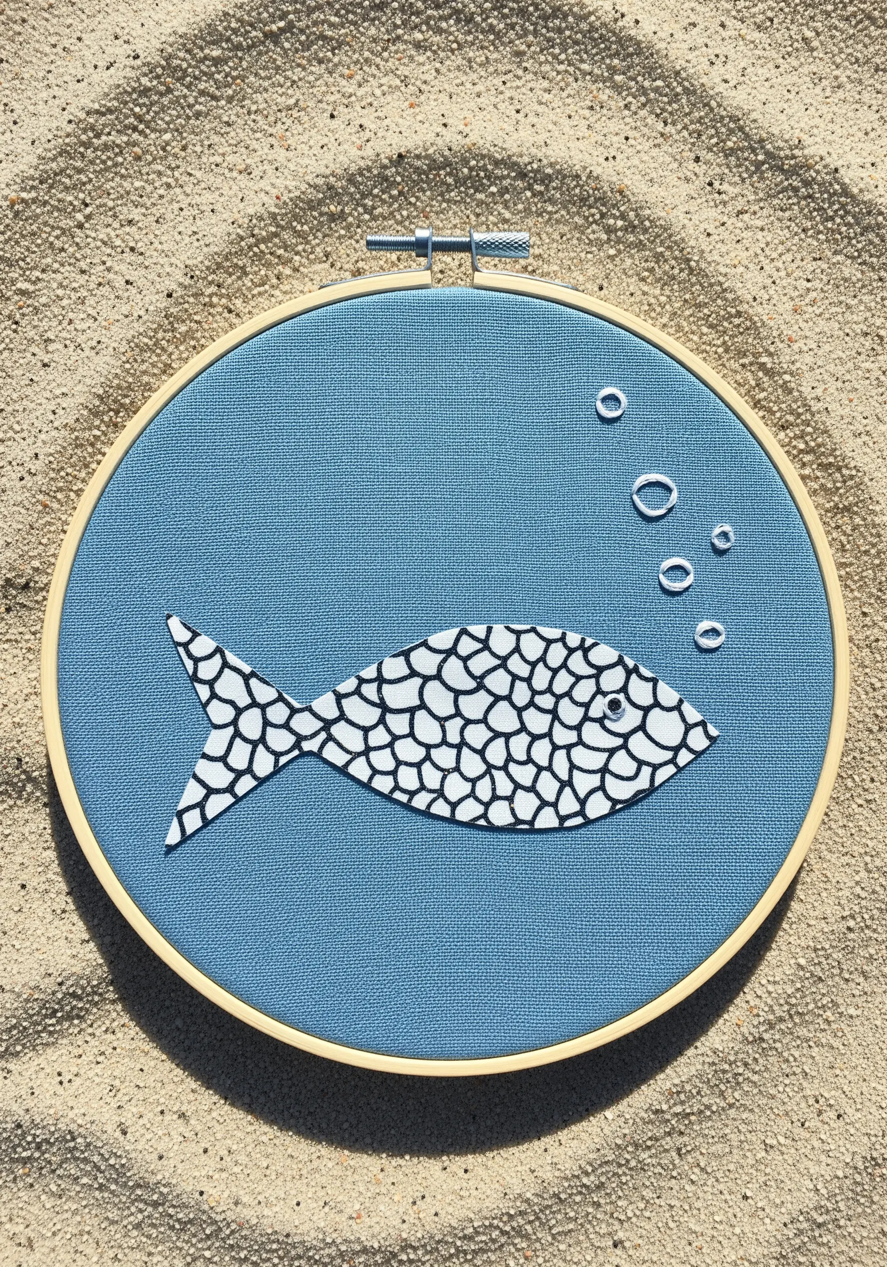 A fish-shaped appliqué made from a black and white scale-patterned fabric.