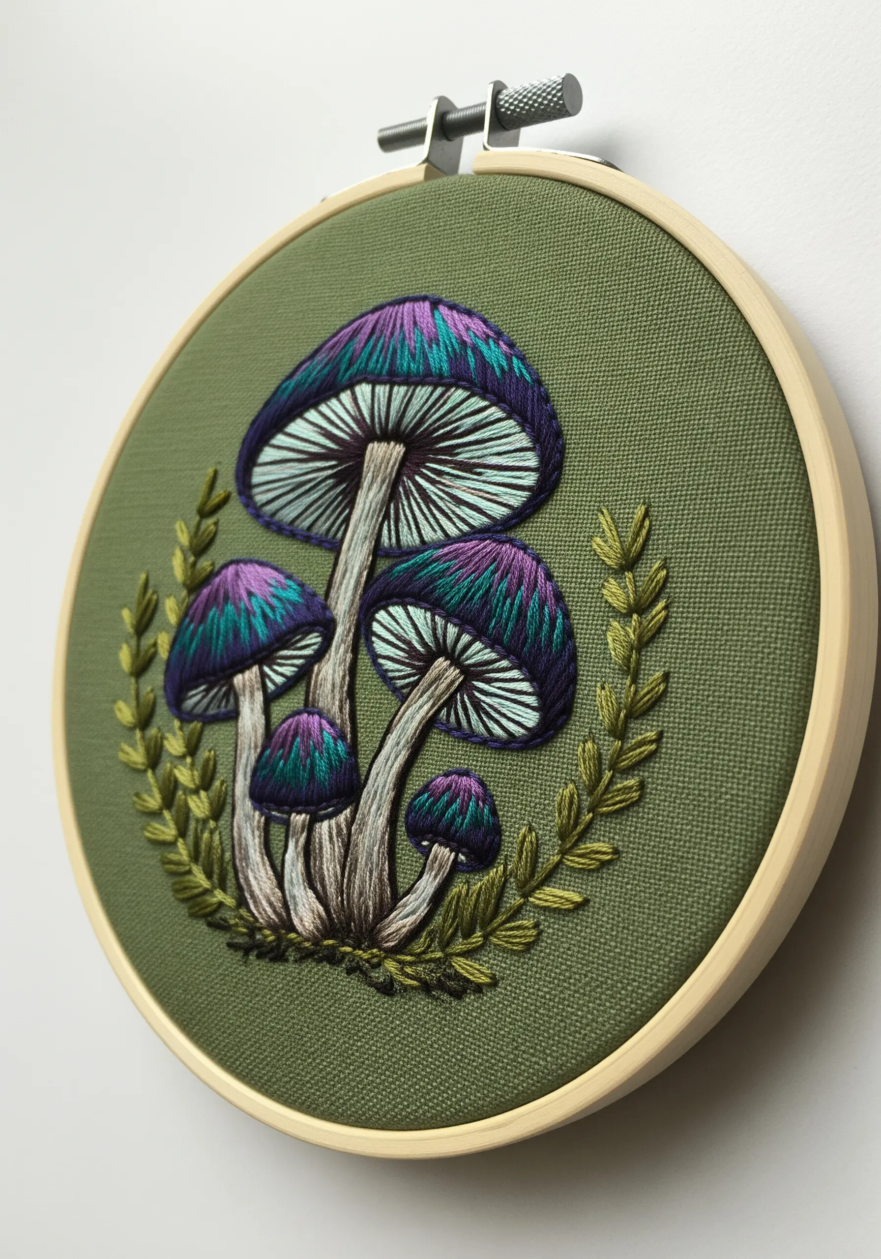 Detailed embroidery of purple and teal mushrooms on olive green fabric.