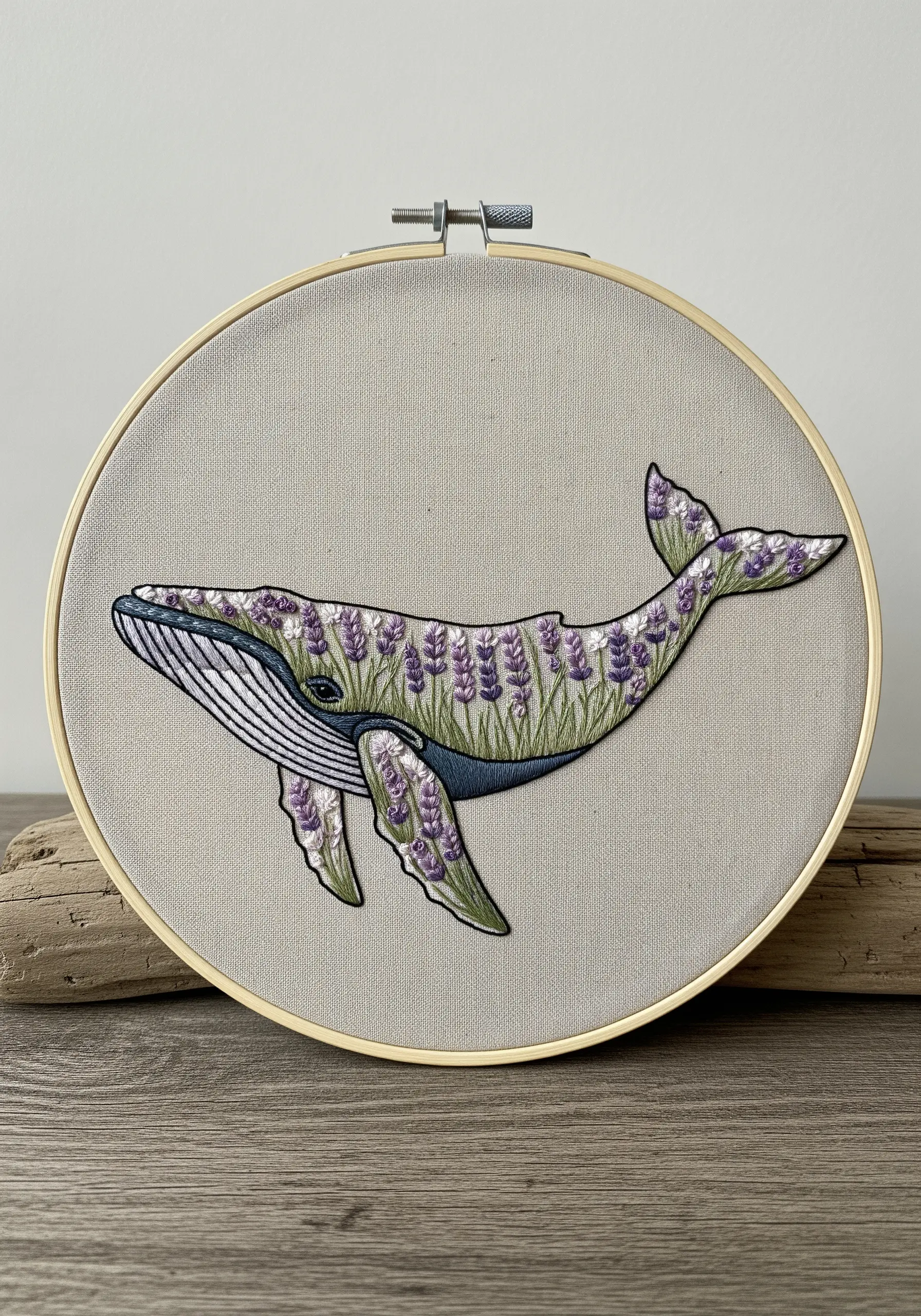 Embroidered whale filled with lavender flowers on neutral linen fabric in a wooden hoop.