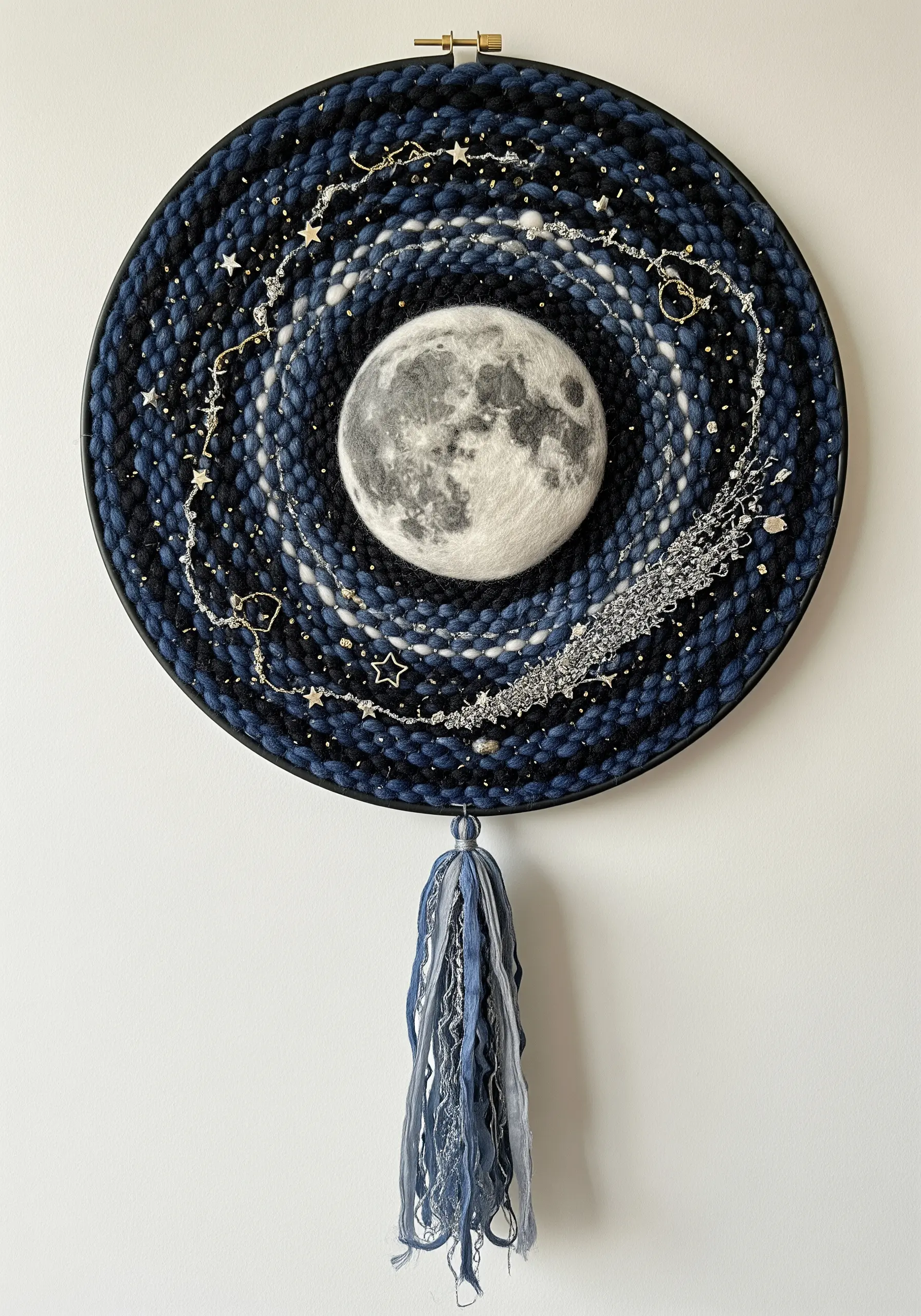 Circular fiber art of a galaxy with a felted moon, silver threads, and stars on a dark background.