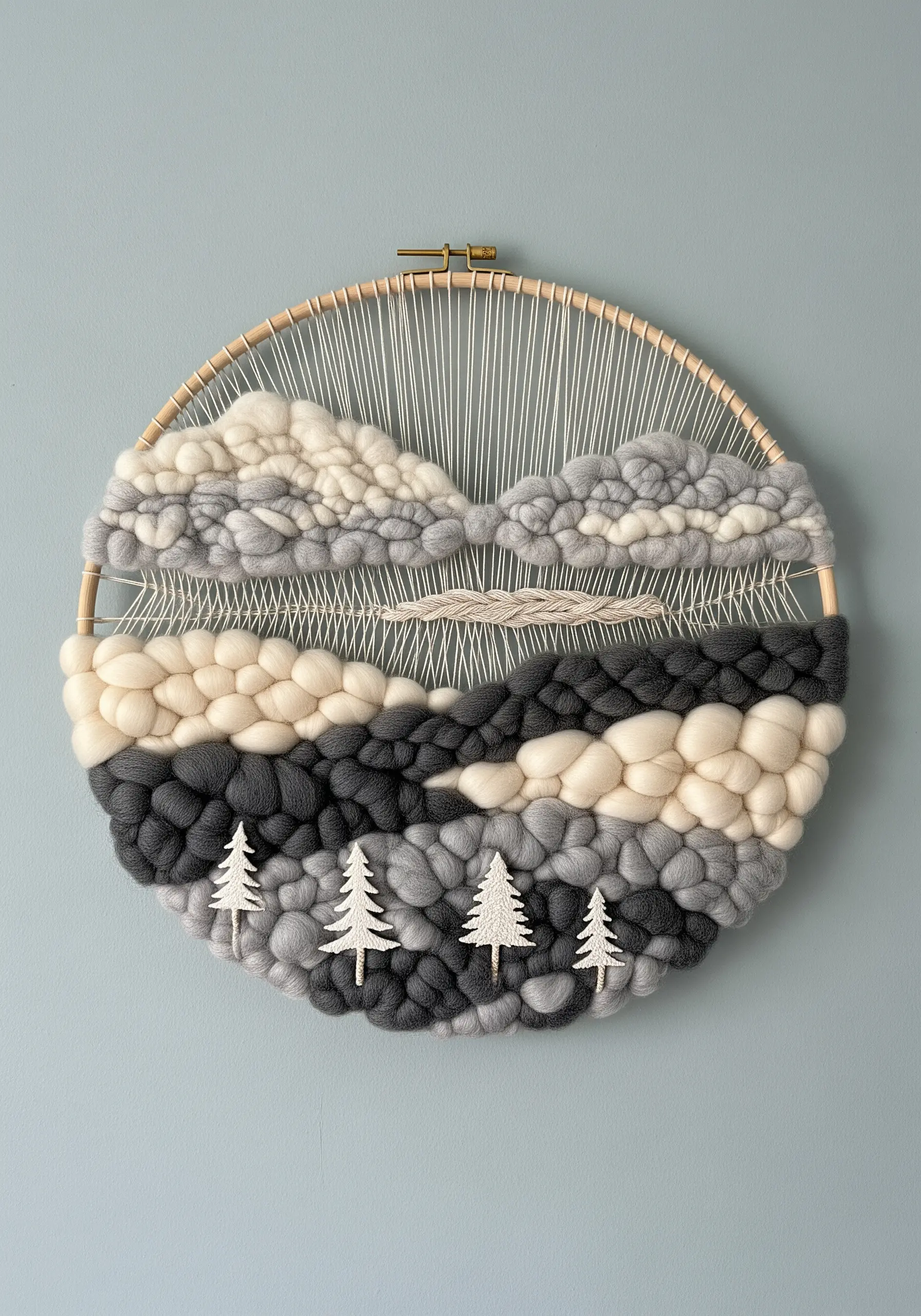 A circular weaving in a hoop depicting a winter landscape with chunky grey and white clouds.