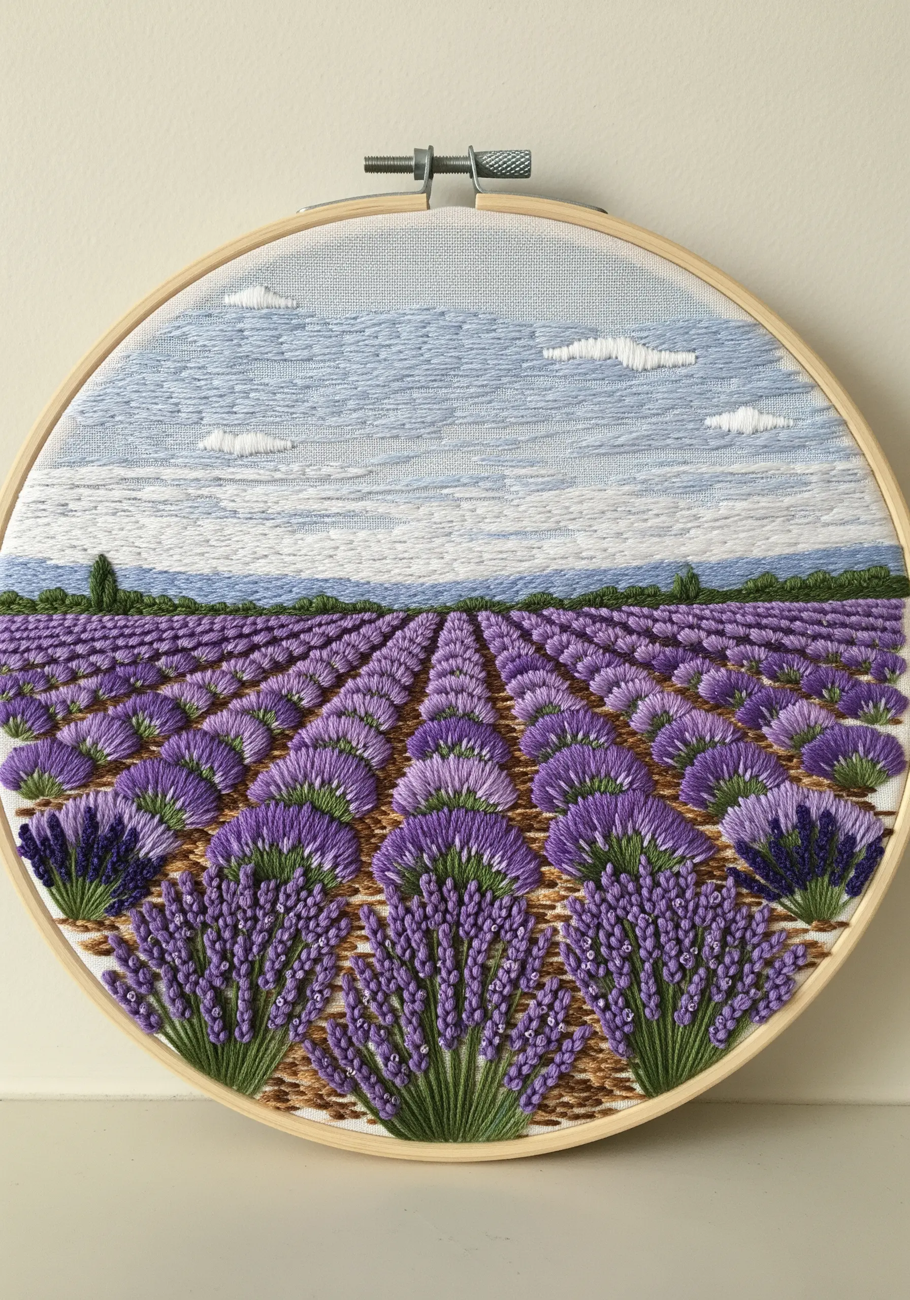An embroidered landscape of a lavender field, showing perspective with rows of purple flowers.
