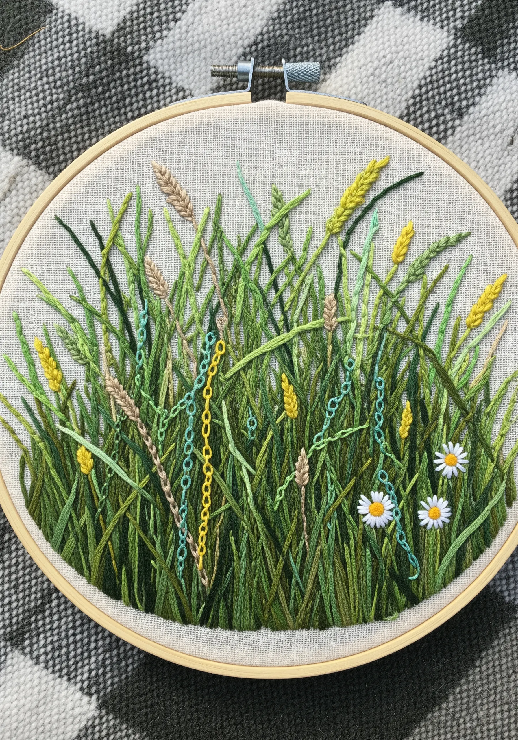 Embroidery of a wildflower meadow with straight stitch grass and delicate chain stitch flowers.
