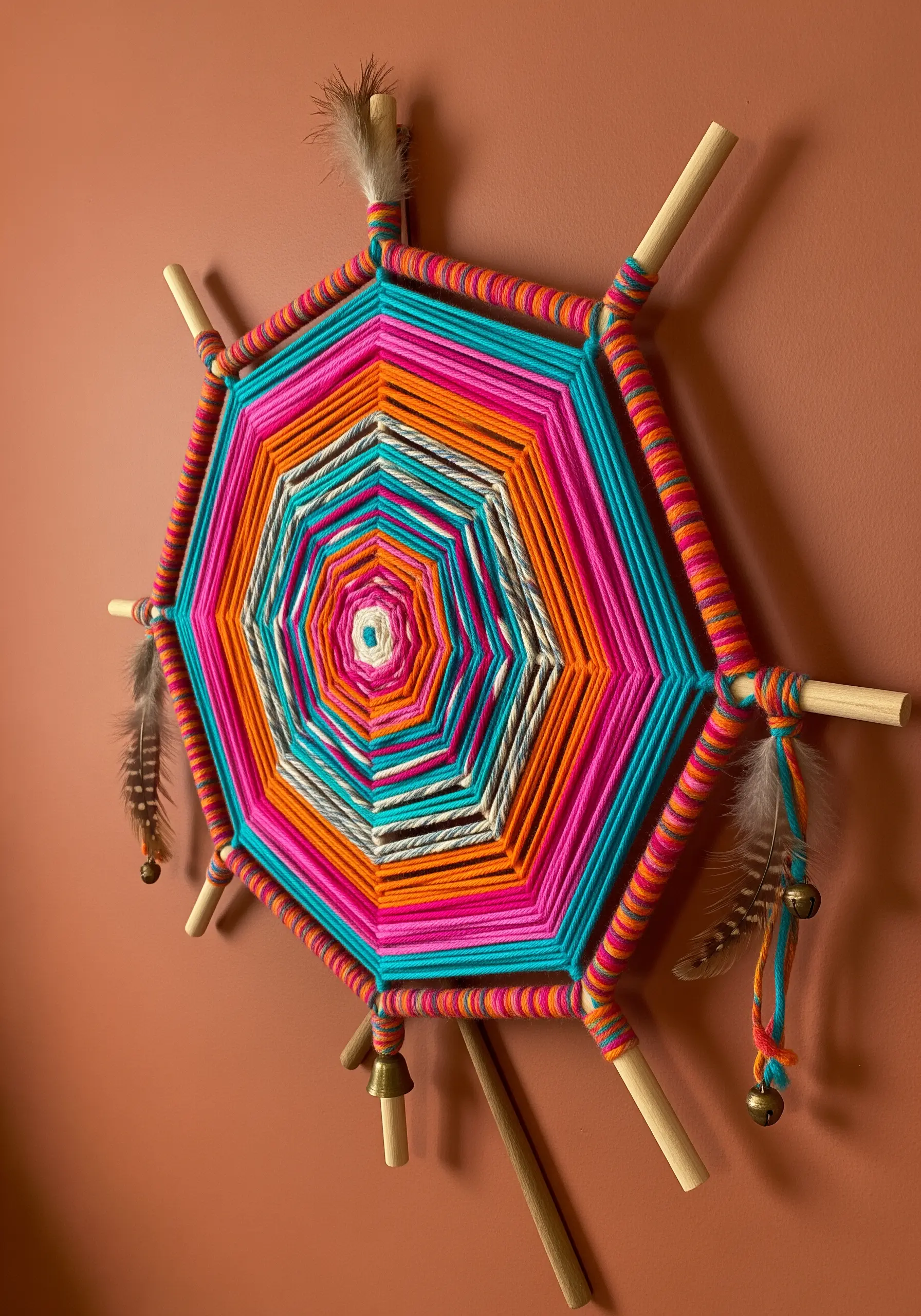 A brightly colored Ojo de Dios woven mandala on a terra cotta wall.