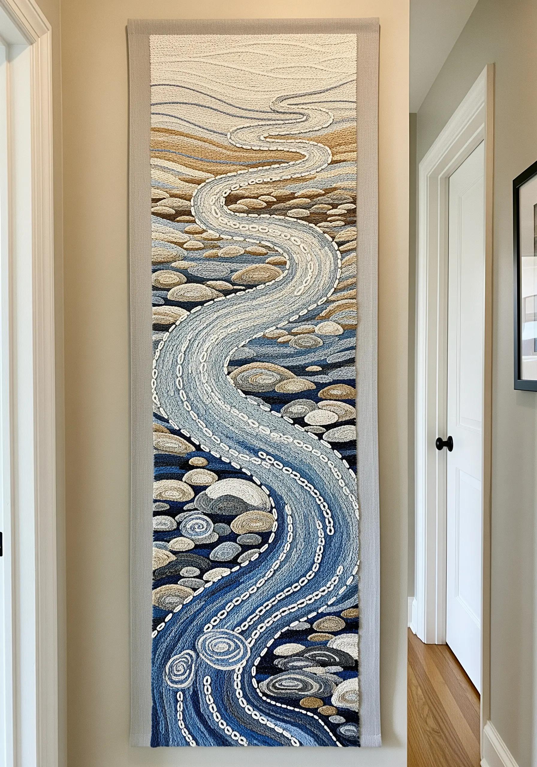 A long, vertical embroidered tapestry of a winding river flowing over textured stones