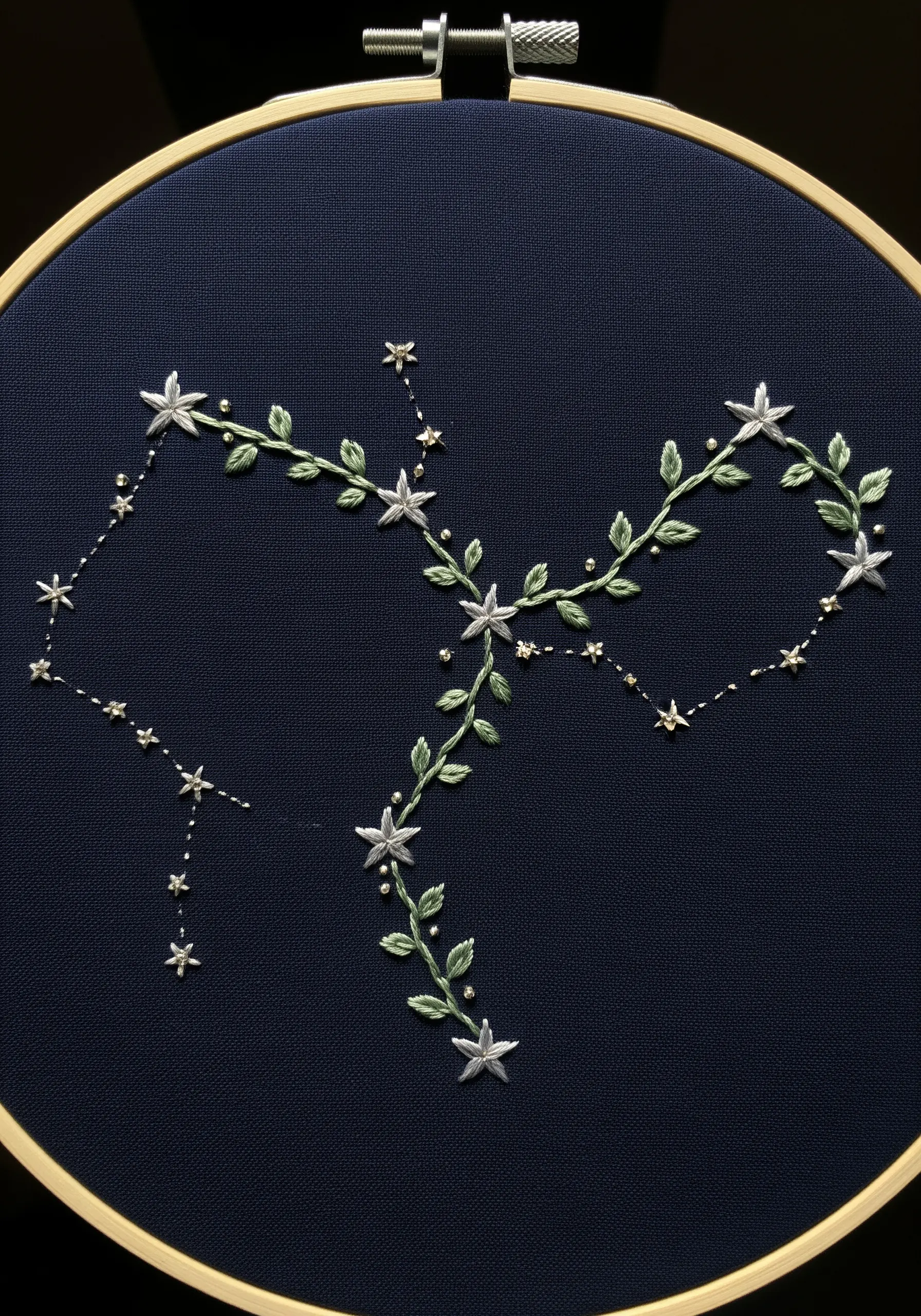 An embroidered constellation made of stars and leafy vines on a dark navy blue background.