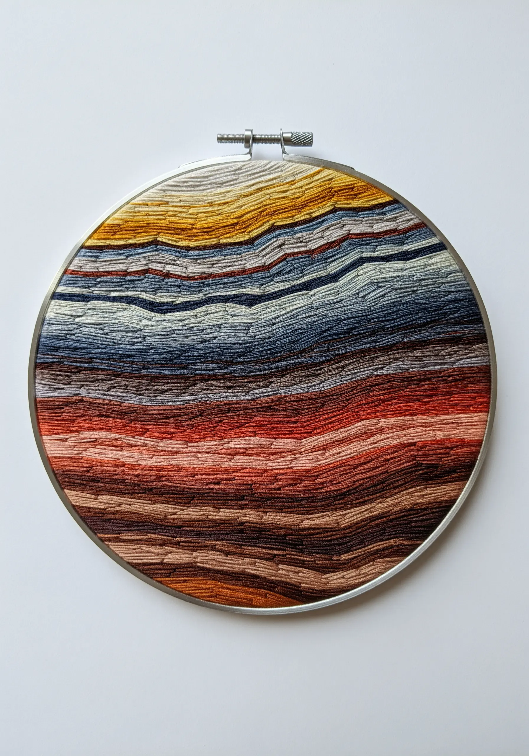 Abstract hoop art with overlapping layers of satin stitch in earthy and blue tones.