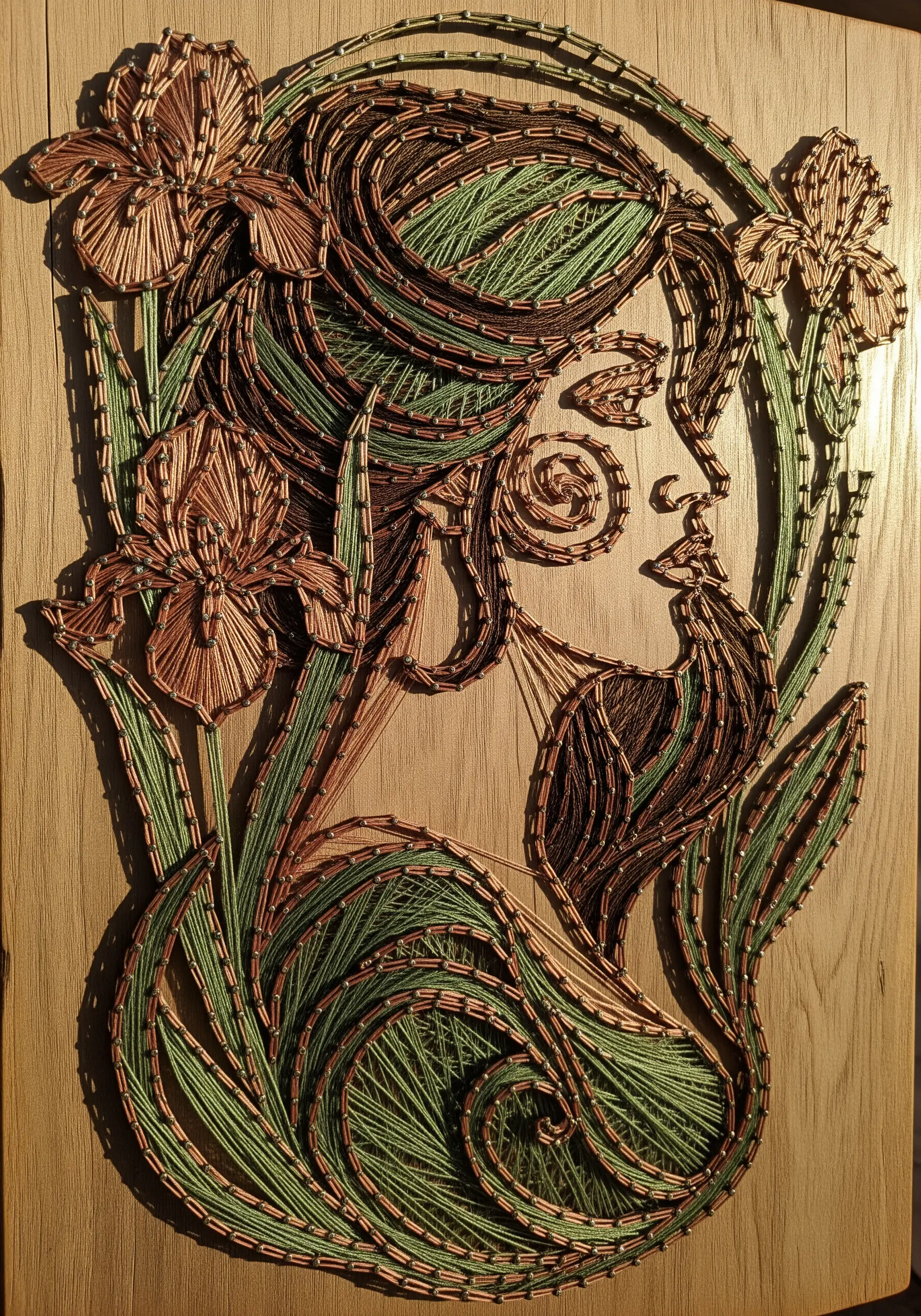 A string art portrait in profile, with hair and background blending into floral and vine motifs.