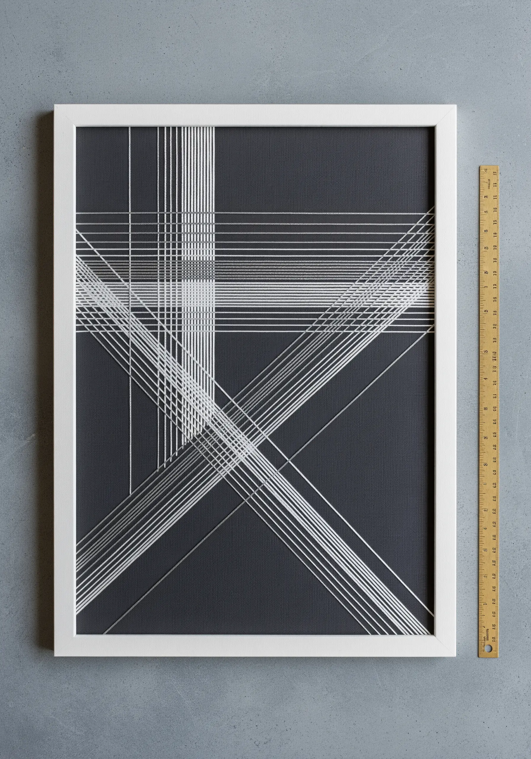 Framed geometric string art with intersecting white lines on a dark gray background.