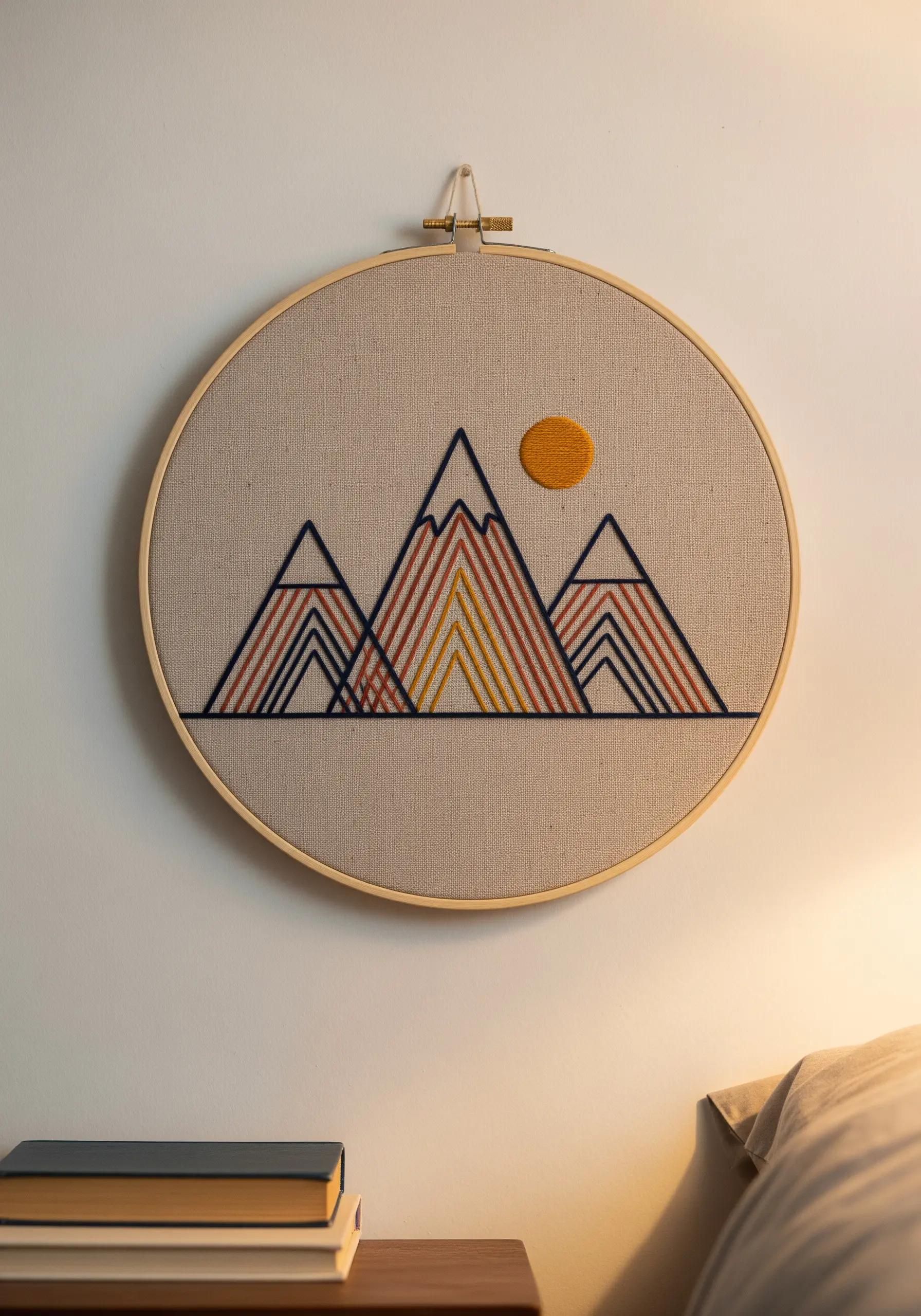 Geometric mountain range in a hoop with directional satin stitches in warm tones.